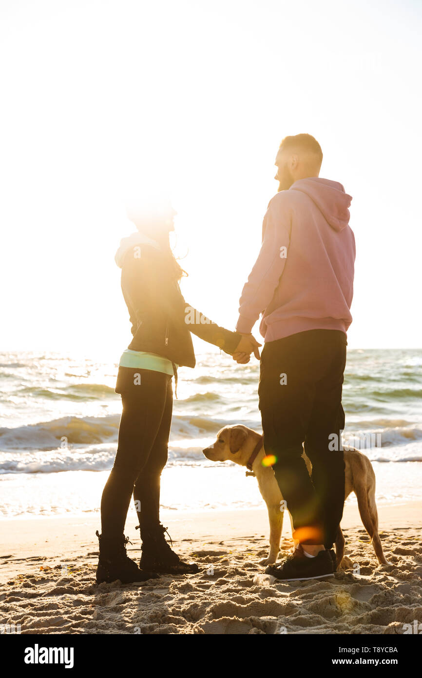 Lovely young couple walking with their dog at the beach Stock Photo - Alamy