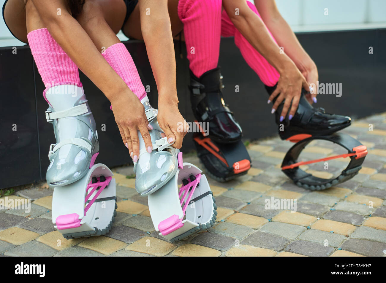 two women put on kangoo jumping boots before workout. Closeup shot