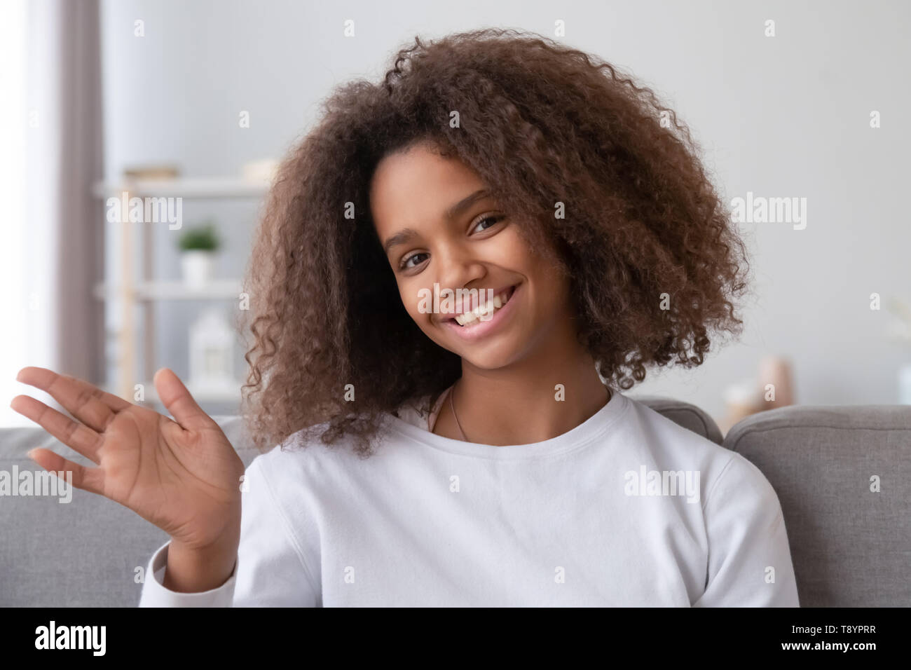 Headshot portrait of smiling African American teenage girl waving hand ...