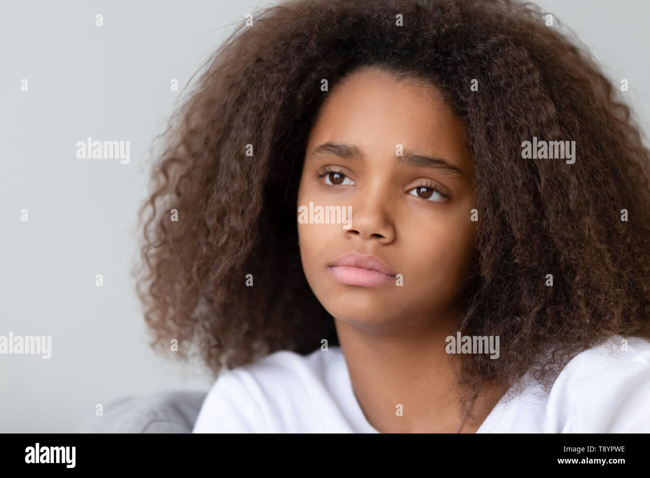 Close up upset thoughtful African American teenage girl sitting alone ...