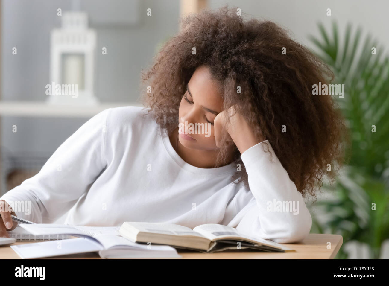 Bored African American teenage girl doing school tasks at home Stock Photo