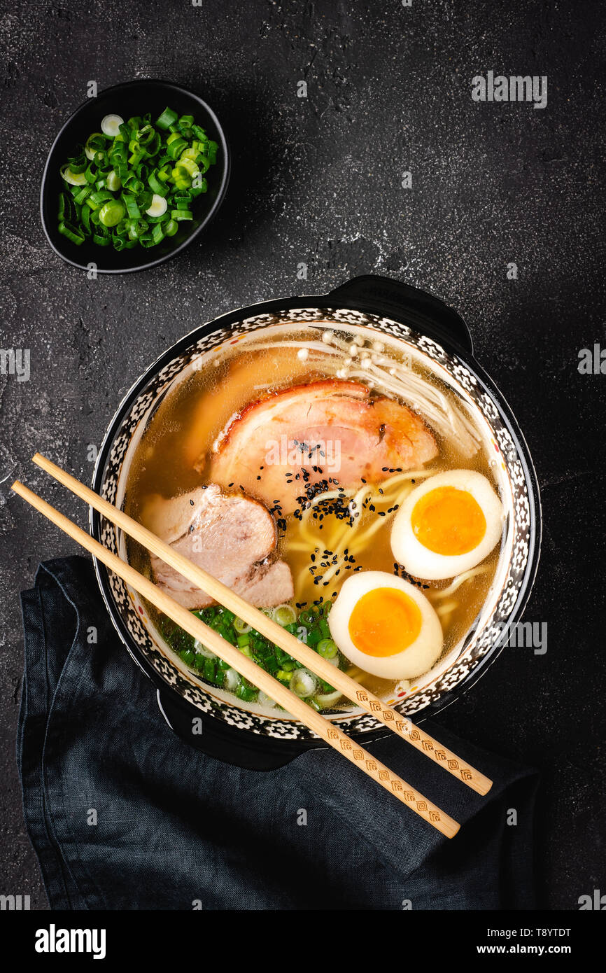 Japanese Ramen Soup with Udon Noodles, Pork, Eggs and Scallion on dark Stone Background Stock Photo