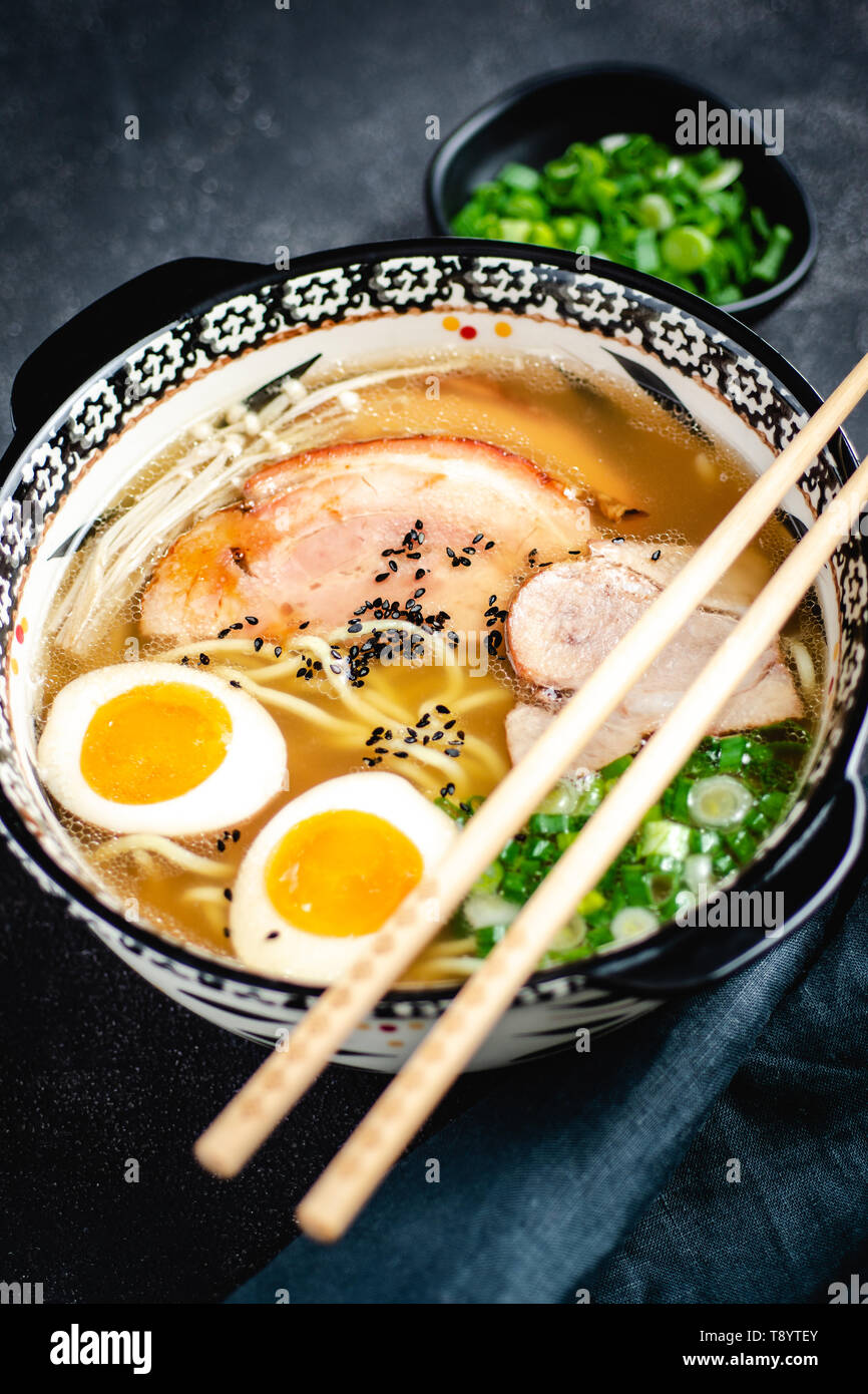 Japanese Ramen Soup with Udon Noodles, Pork, Eggs and Scallion on dark Stone Background Stock Photo