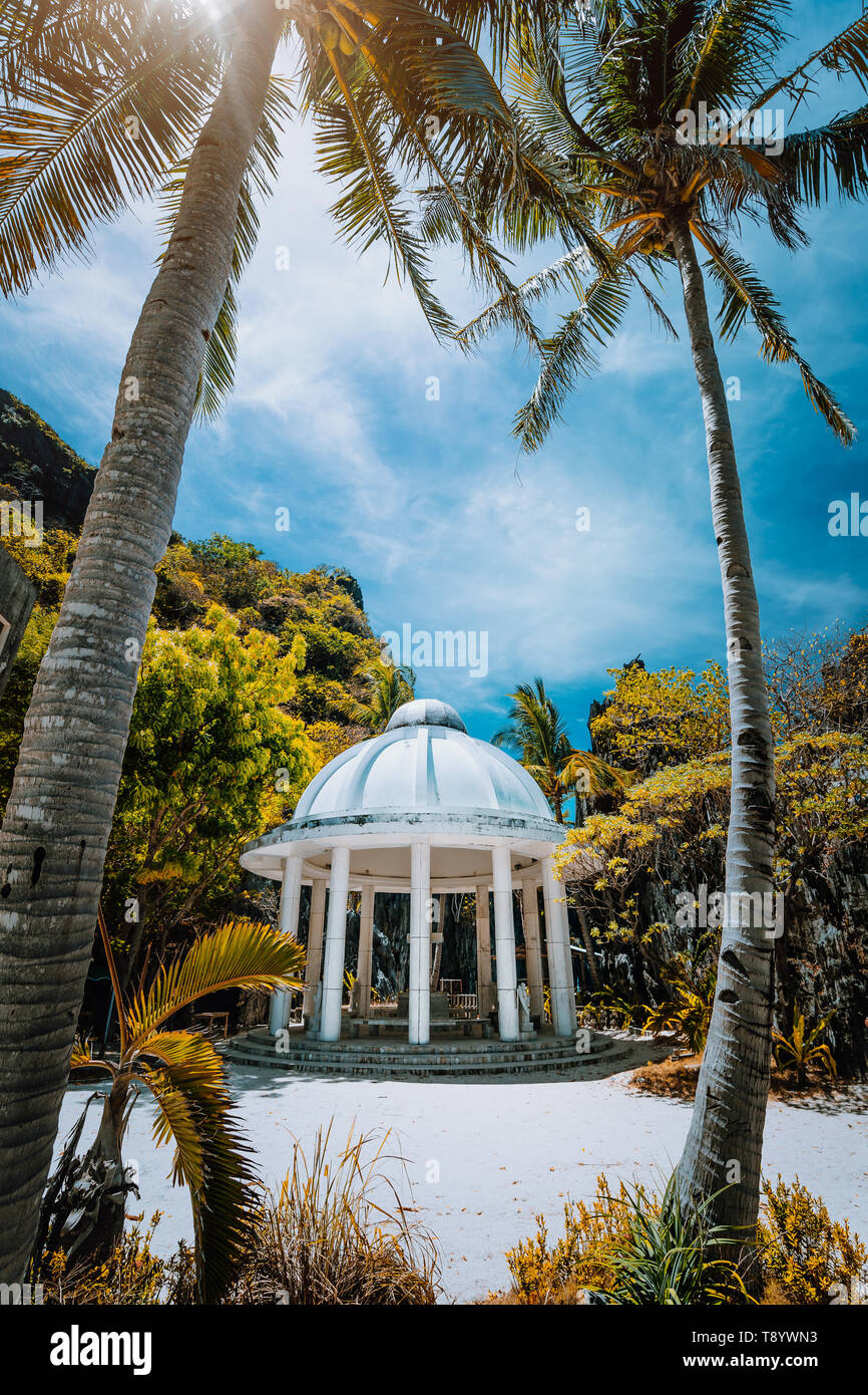 Abandoned Matinloc Shrine between two palm trees at the western coast of Matinloc Island at Palawan, Philippines. Stock Photo