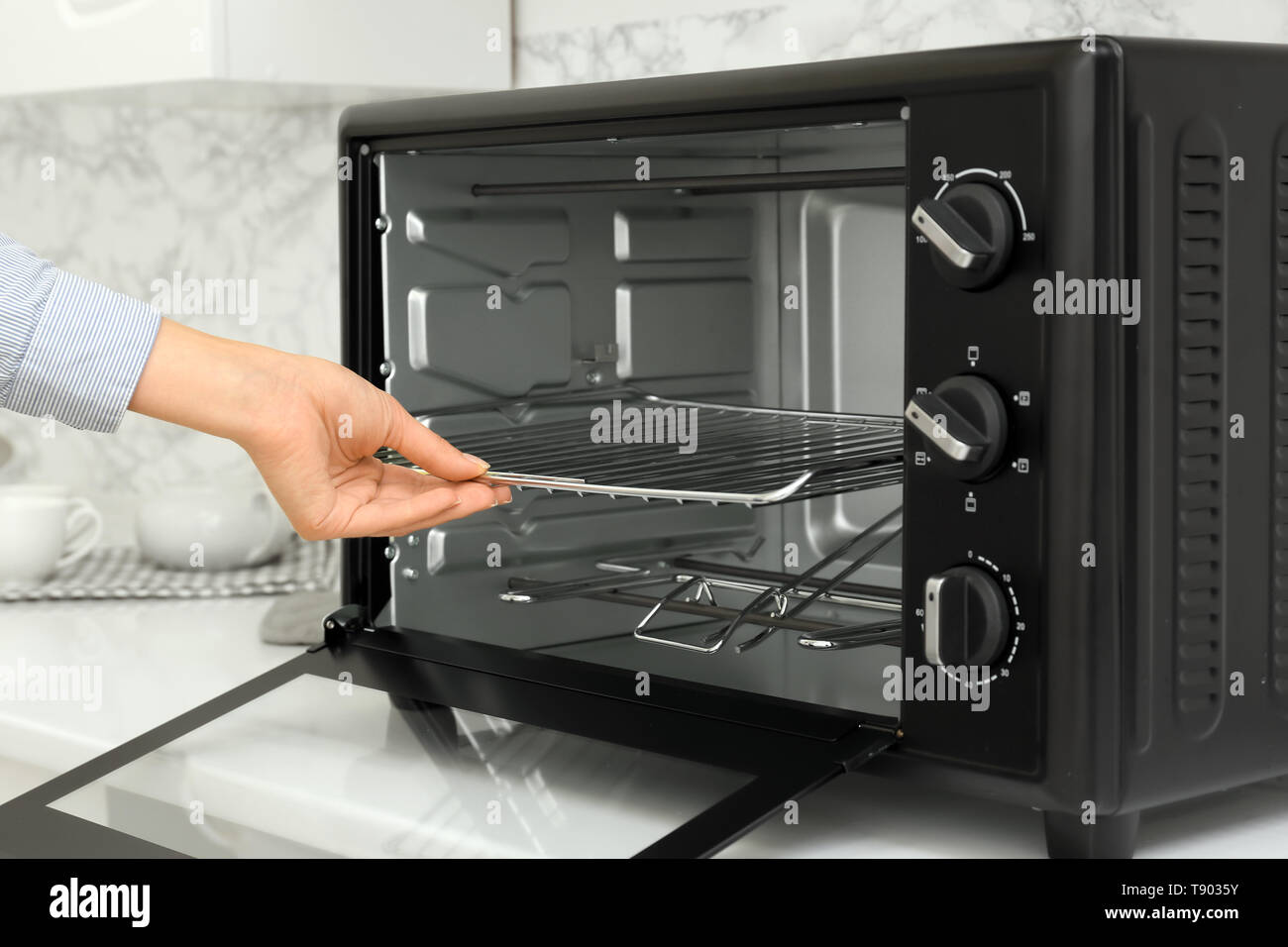 Woman putting rack into electric oven Stock Photo Alamy
