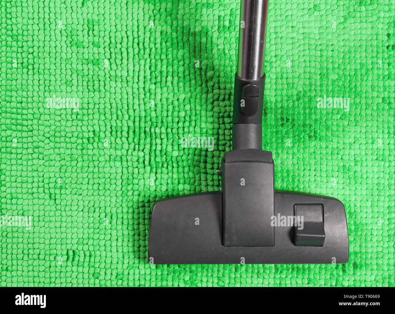 Close-up of a vacuum cleaner on a green colored rug Stock Photo