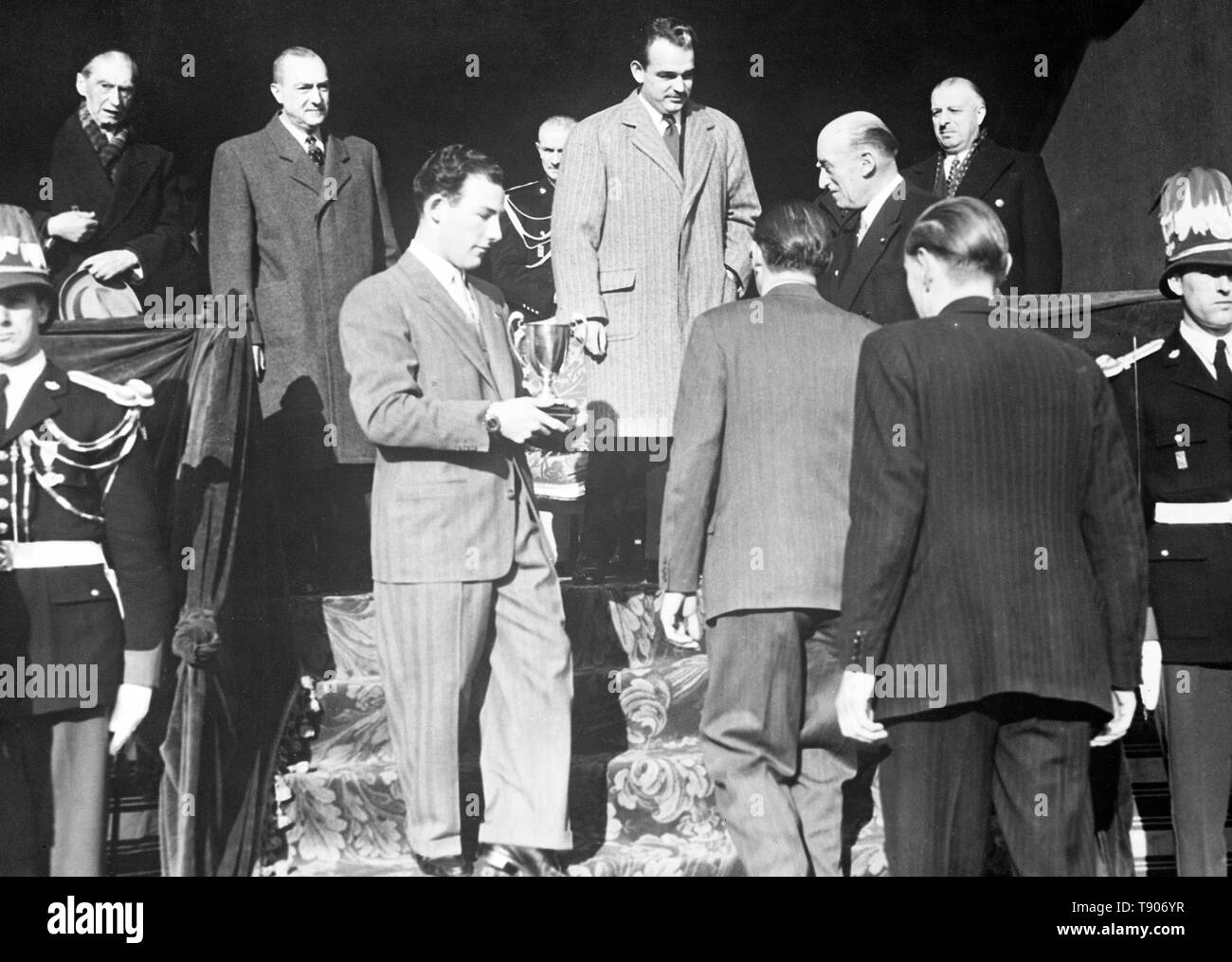 Stirling Moss, young British driver placed second in the 1952 Monte Carlo Rally (won by Britain for the first time in 20 years), receives his trophy from Prince Rainier III of Monaco. Stirling Moss and his co-driver Desmond Scannell were second to Sidney Allard and G. Warburton, driving an Allard, product of Allard's own London workshop. Stock Photo