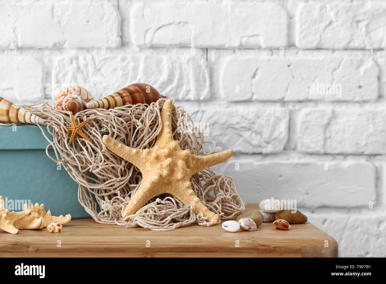 Starfish, seashells and pebbles as decorations on table near white