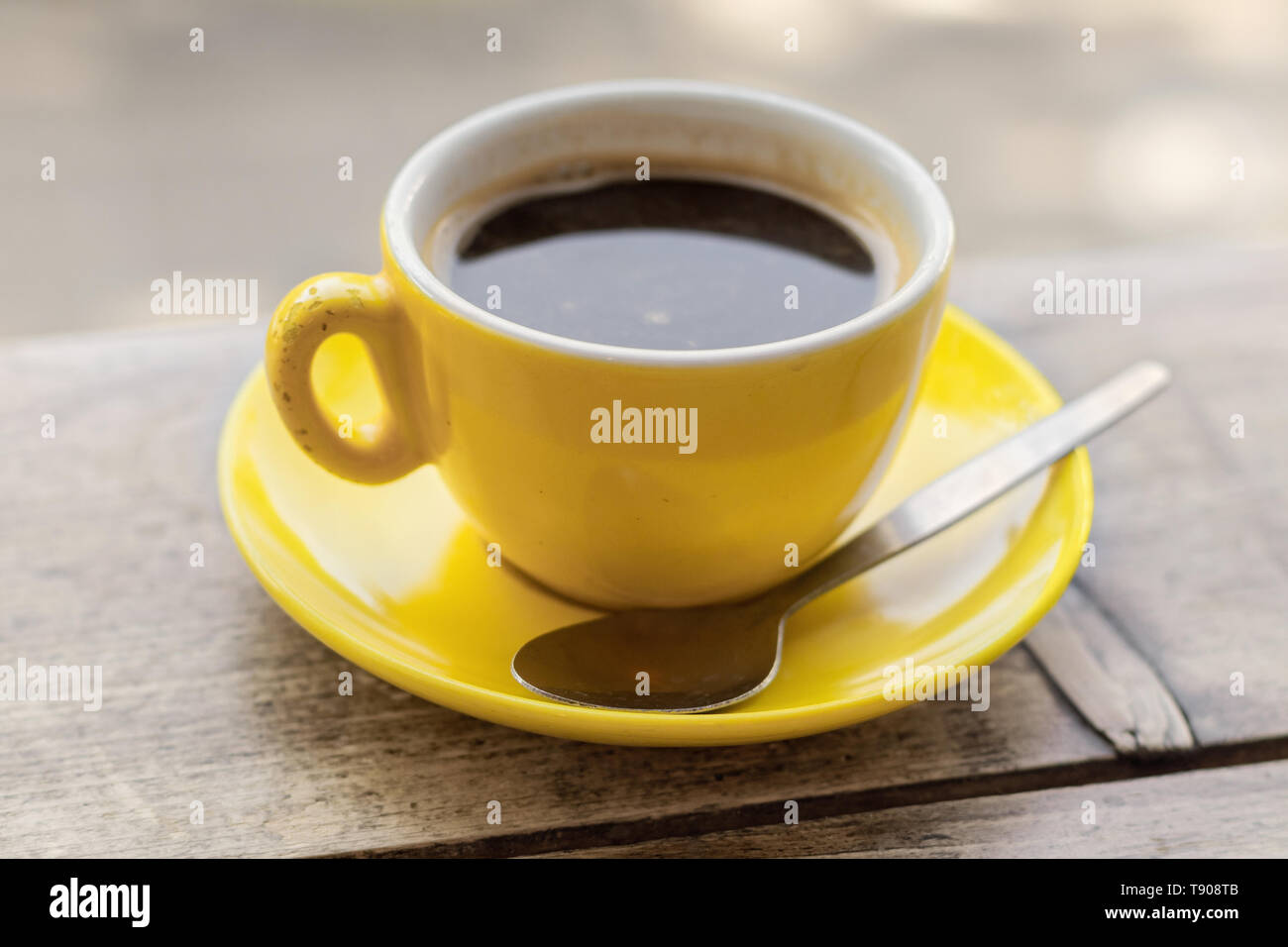 Chipped yellow coffee cup and saucer on a wooden table, closeup with a shallow depth of field Stock Photo