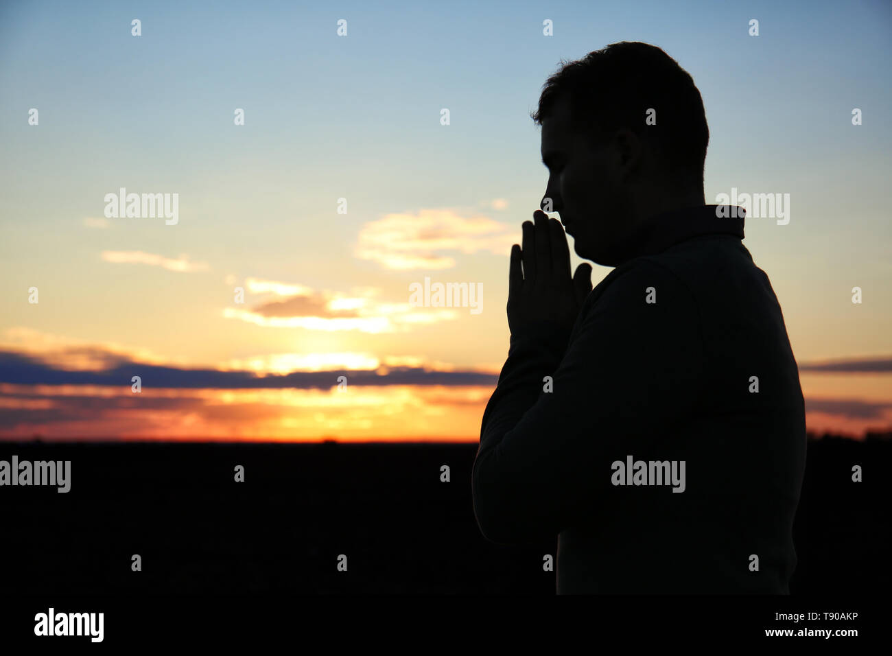 Religious man praying outdoors at sunset Stock Photo Alamy