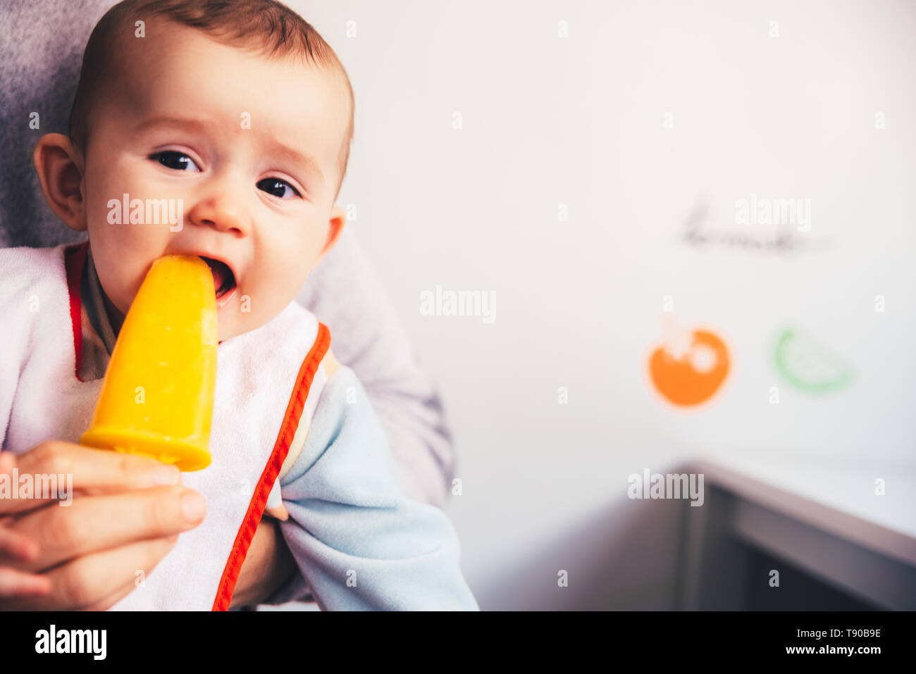 Baby savoring an orange ice cream. Stock Photo