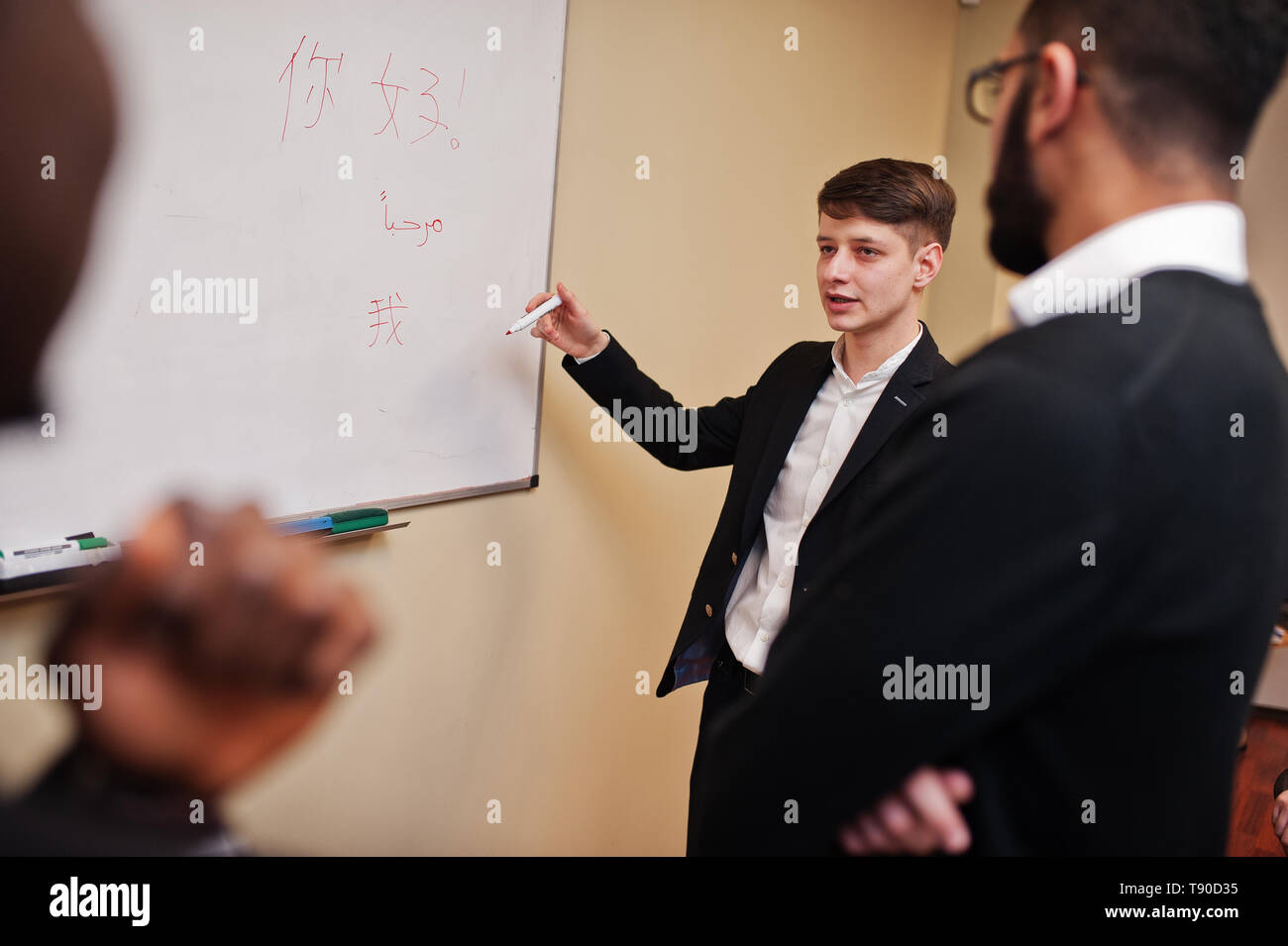 Male colleagues working in team cooperate , multiracial crew of employees concentrated on project planning against board and discussing ideas. Stock Photo