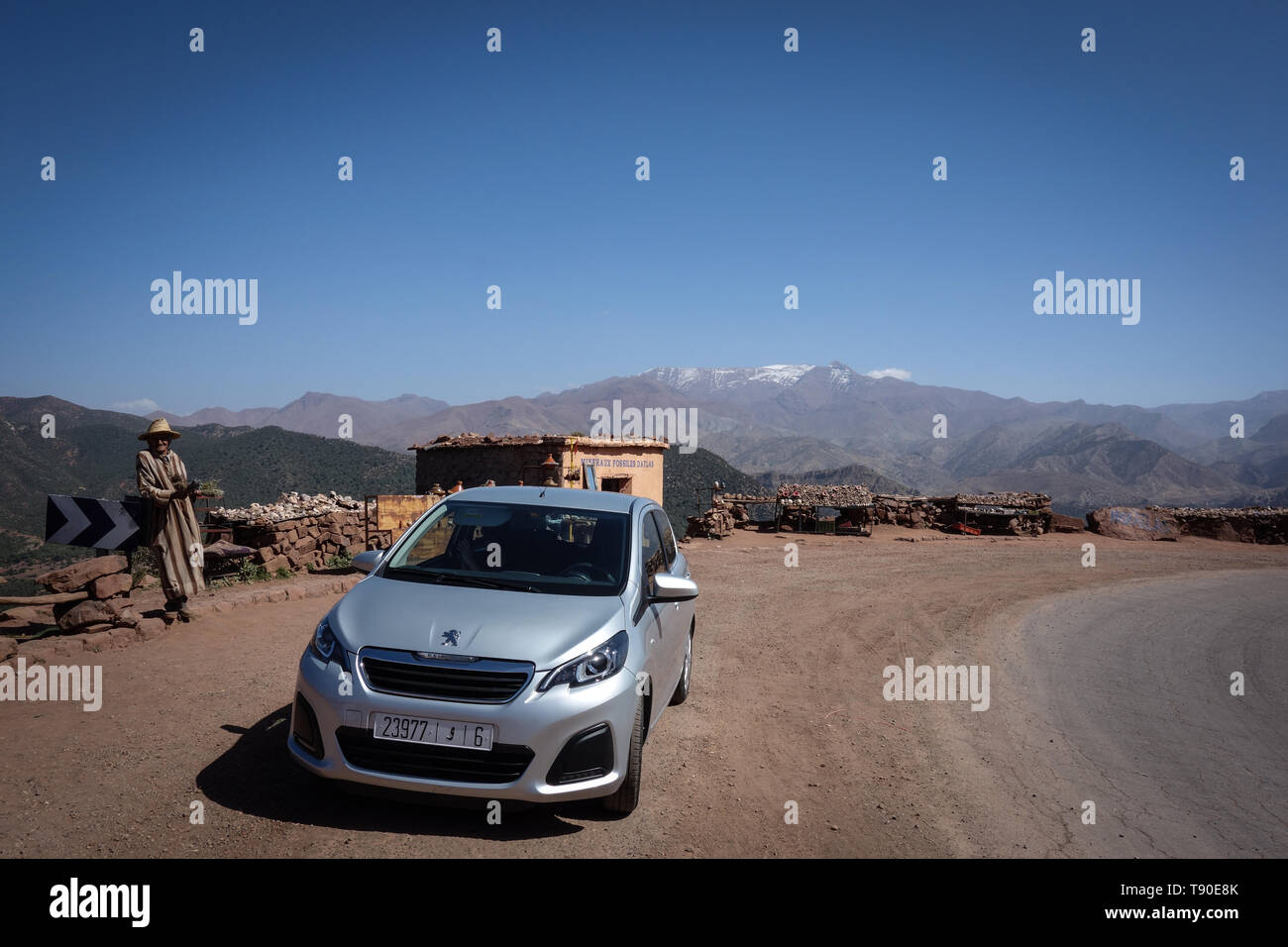 Aguelmouss, Morocco - March 19th, 2019: High Atlas Mountains outlook with a Maroccan selling some herbs and a compact car Stock Photo