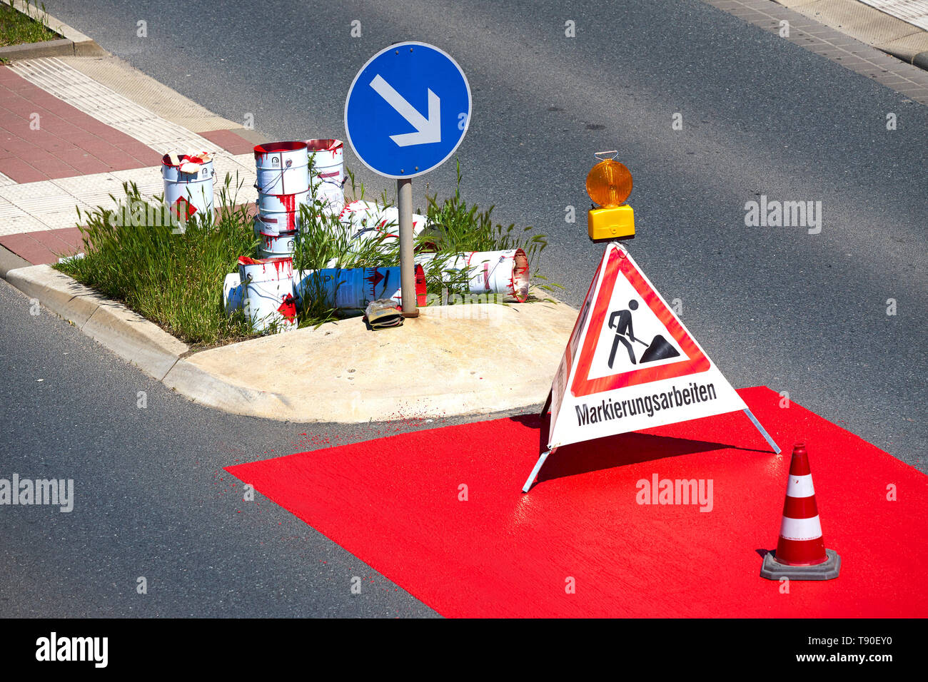 Workers carrying out marking work on a road that is marked with red paint Stock Photo