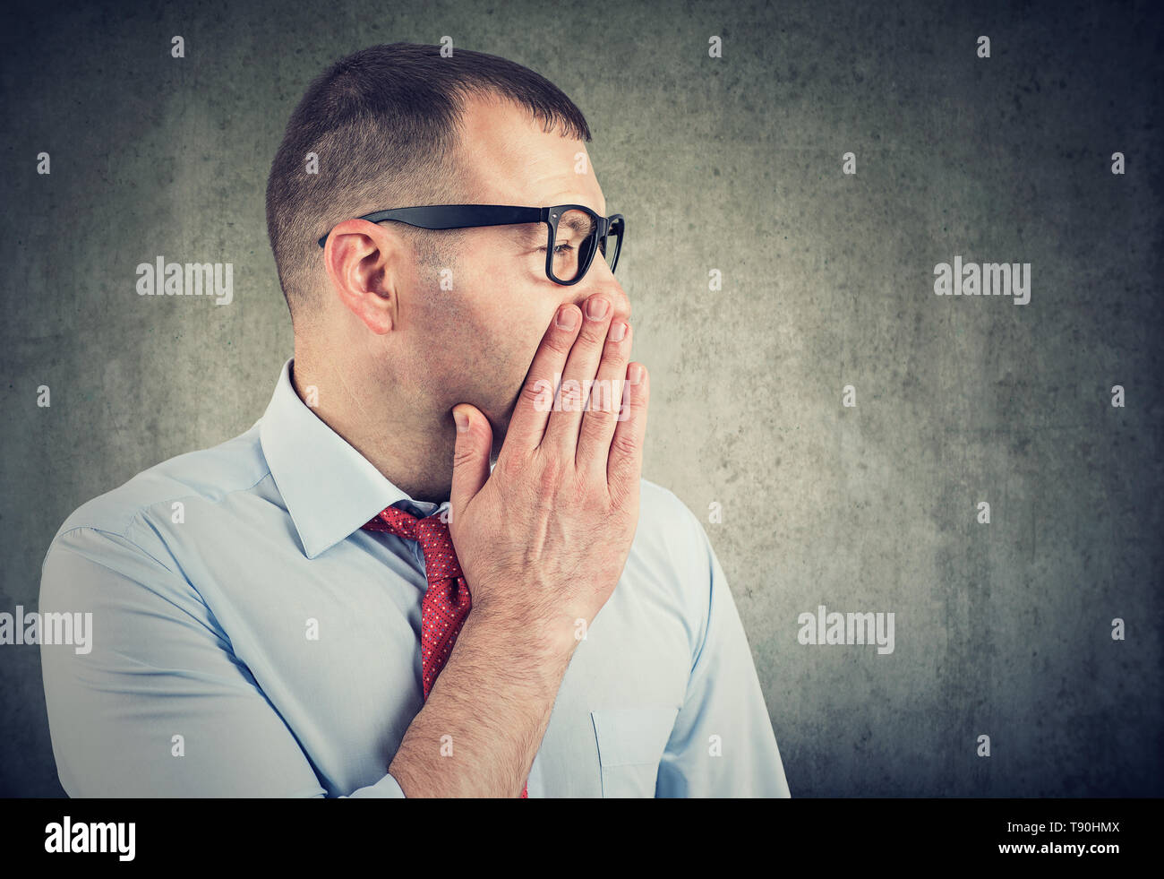 Businessman covering mouth while gossiping and telling secrets in whisper. Stock Photo