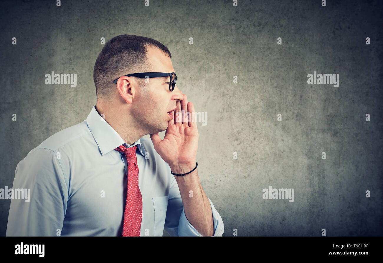 Businessman covering mouth while gossiping and telling secrets in whisper. Stock Photo