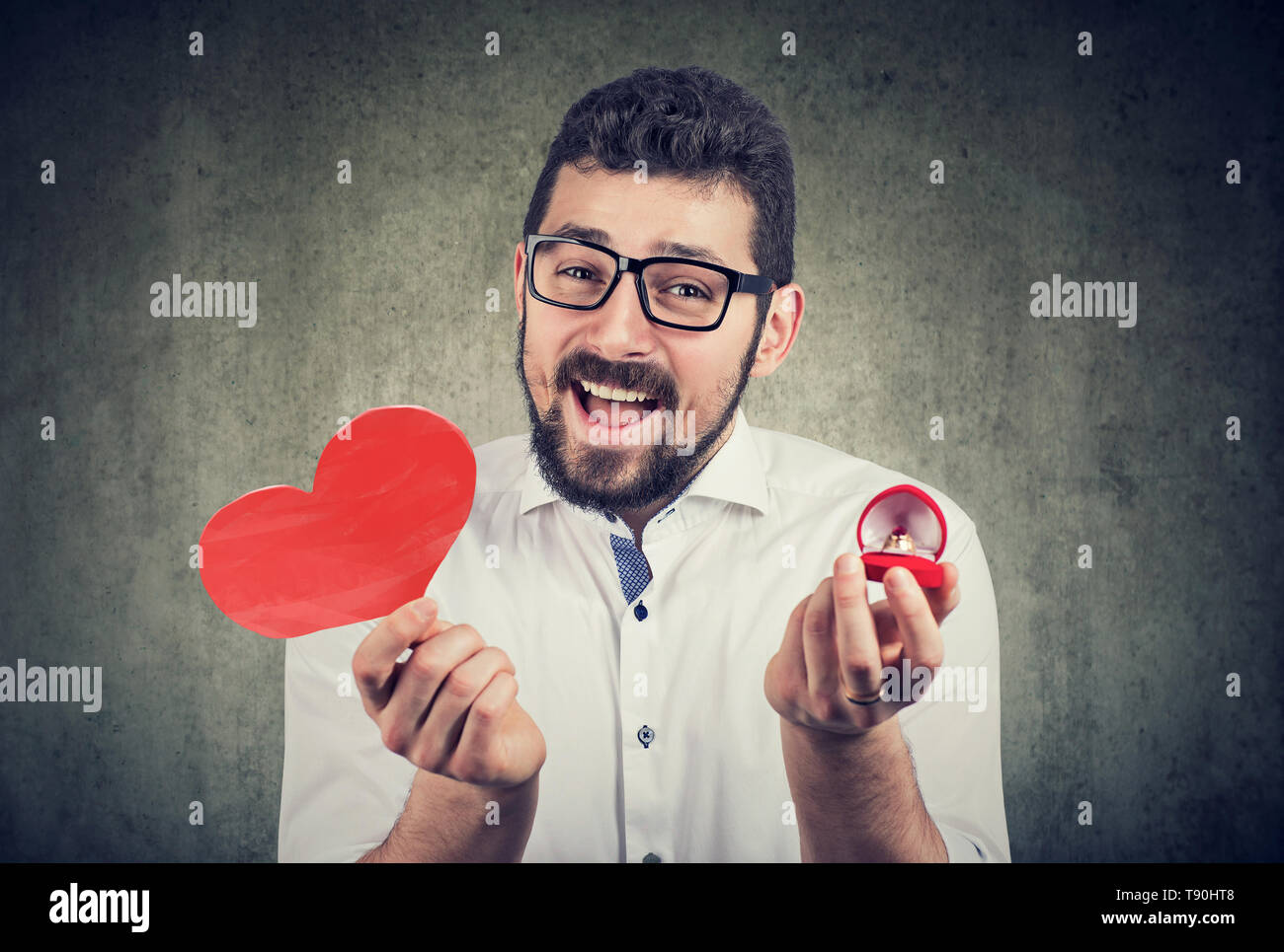 Super excited man with red heart shape wedding ring box. Romantic proposal concept Stock Photo