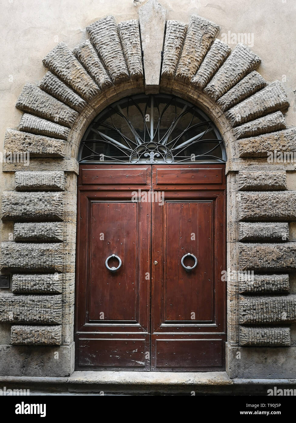 Ancient wooden portal with carved stone arch of an Italian medieval building. Stock Photo