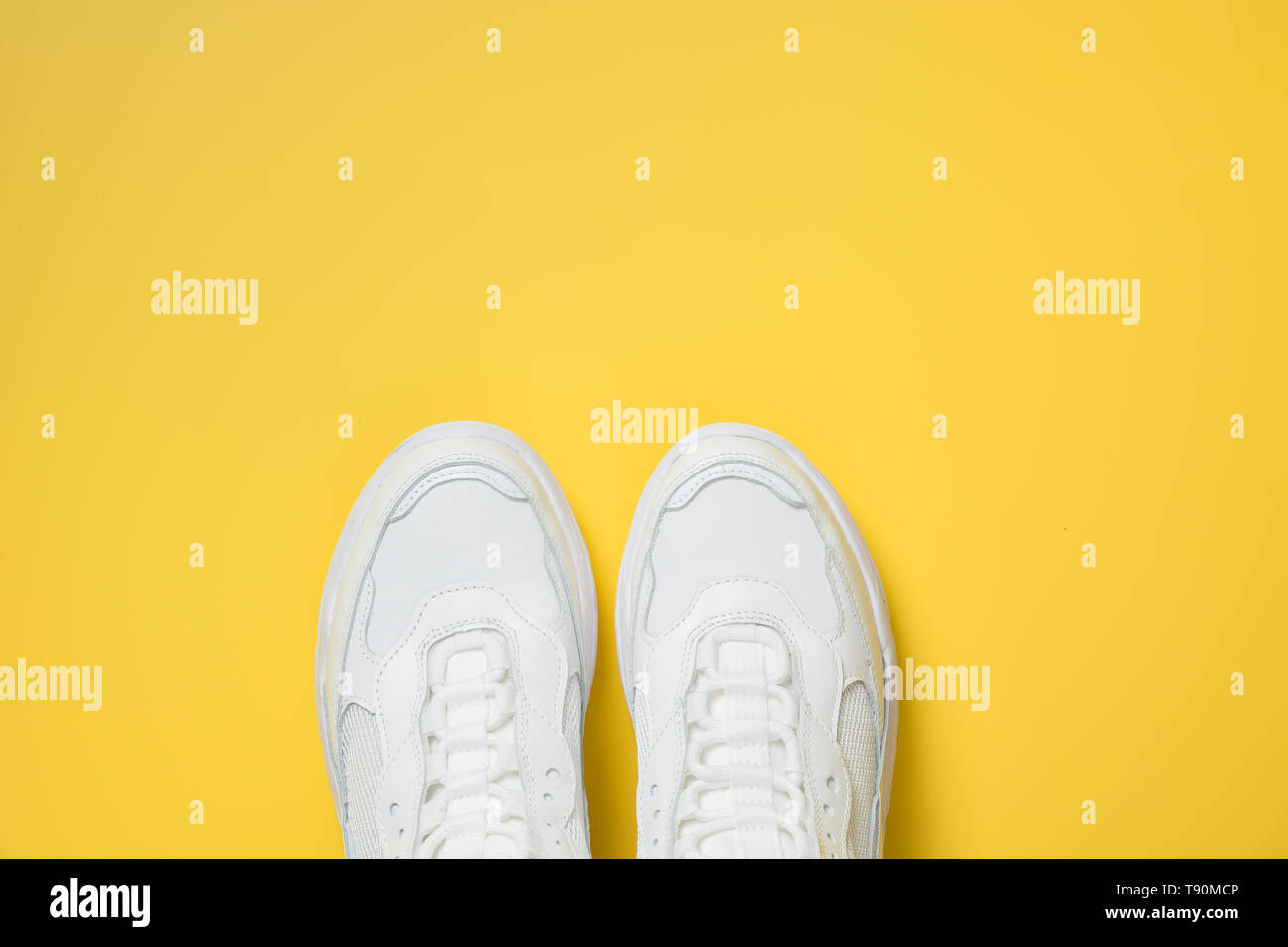Pair of white female sneakers on yellow. Flat lay, top view minimal background. Magazine concept. Stock Photo