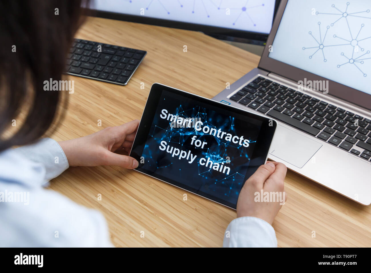 Business Female Using Smart Contracts For Supply chain. Illustration of Ethereum Blockchain on the Screen of Tablet, PC and Laptop. Stock Photo