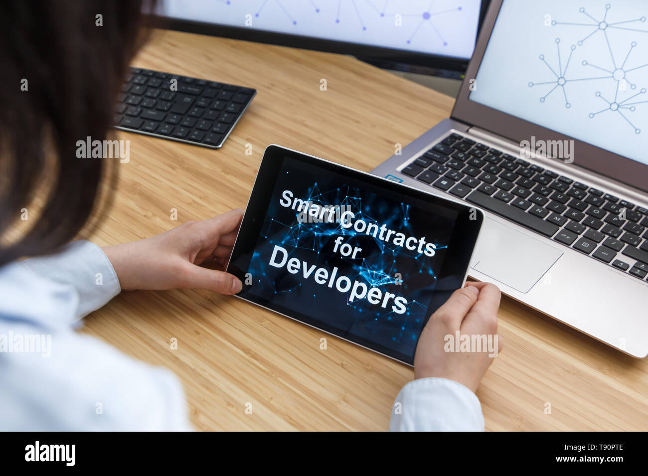 Business Female Using Smart Contracts For Developers. Illustration of Ethereum Blockchain on the Screen of Tablet, PC and Laptop. Stock Photo