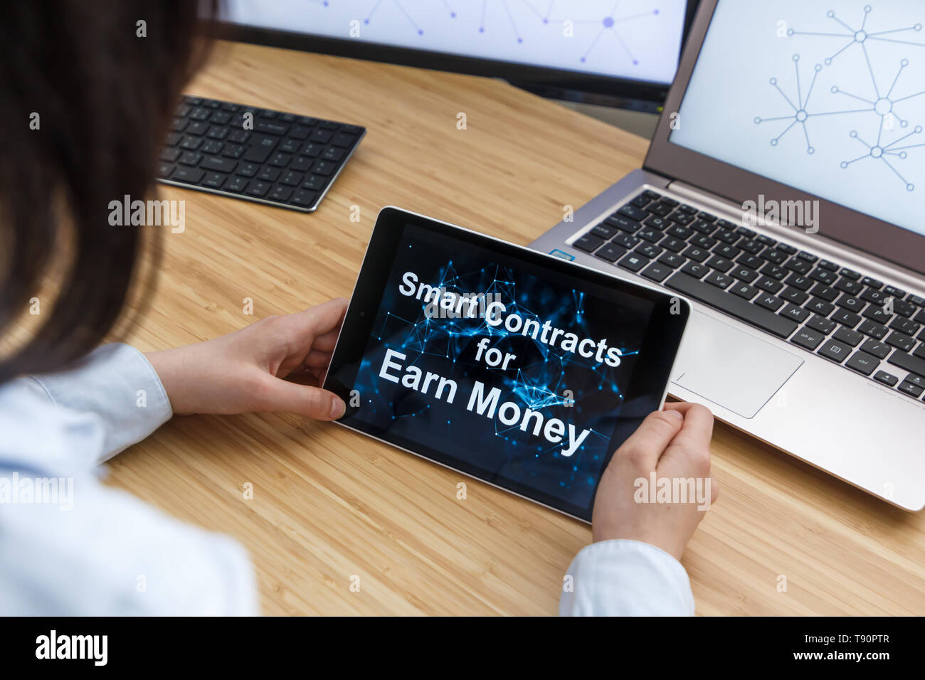 Business Female Using Smart Contracts For Earn Money . Illustration of Ethereum Blockchain on the Screen of Tablet, PC and Laptop. Stock Photo