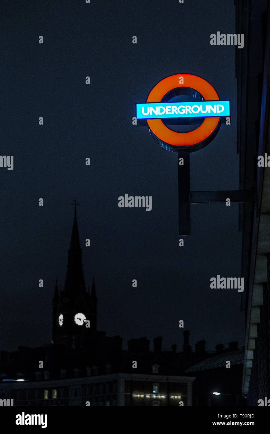 Illuminated Underground sign with the tower of St Pancras Station in the background, London, UK Stock Photo