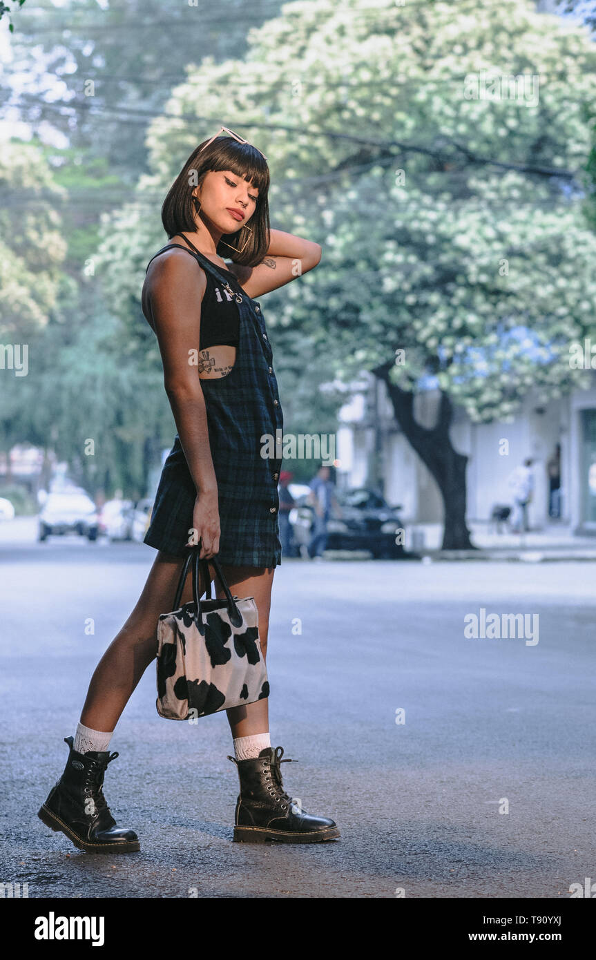 Cute young fashion latina girl with a square cut walking in the street in  overalls Stock Photo - Alamy