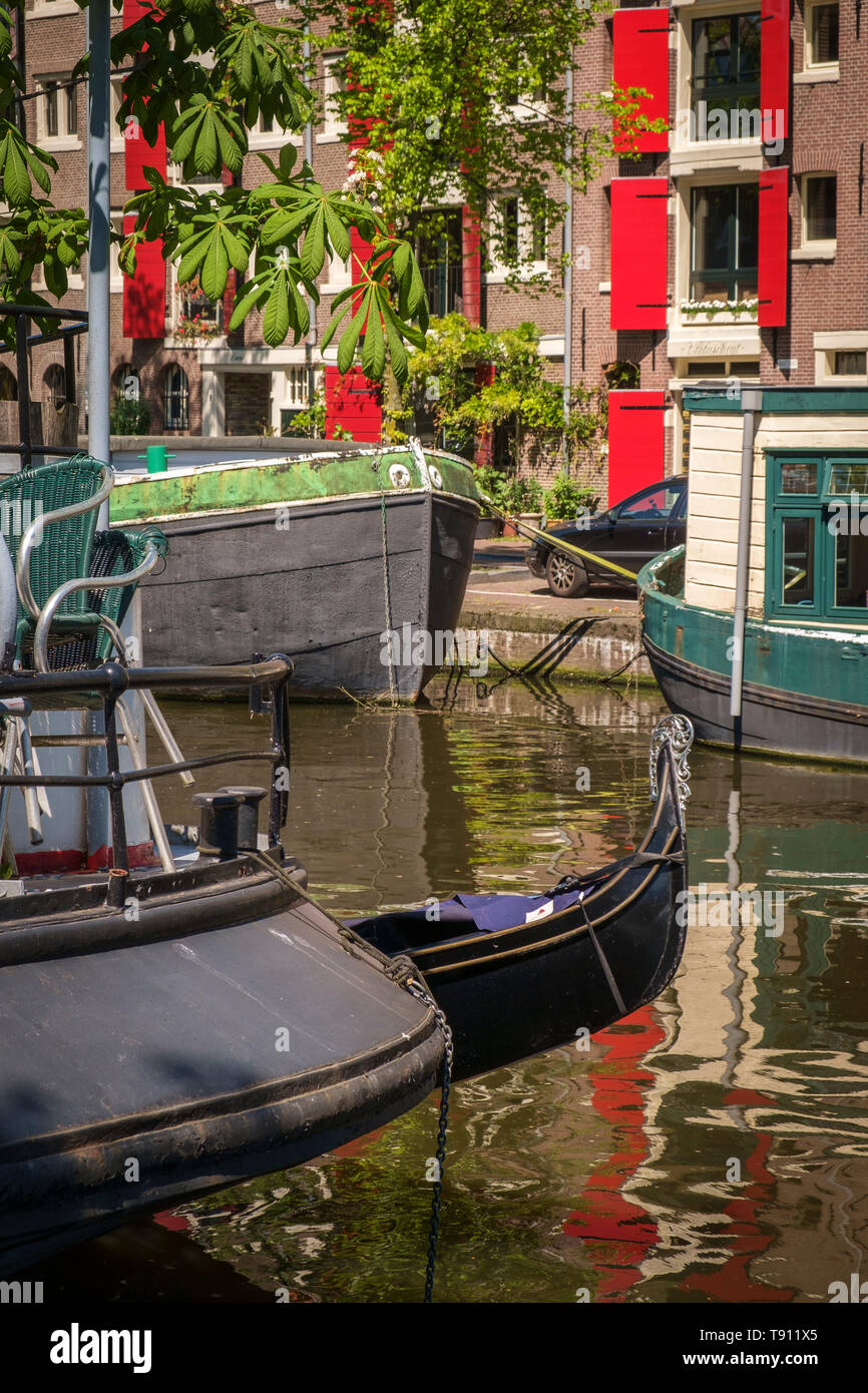 The prow of a Venetian gondola moored next to a houseboat on an Amsterdam canal. Stock Photo