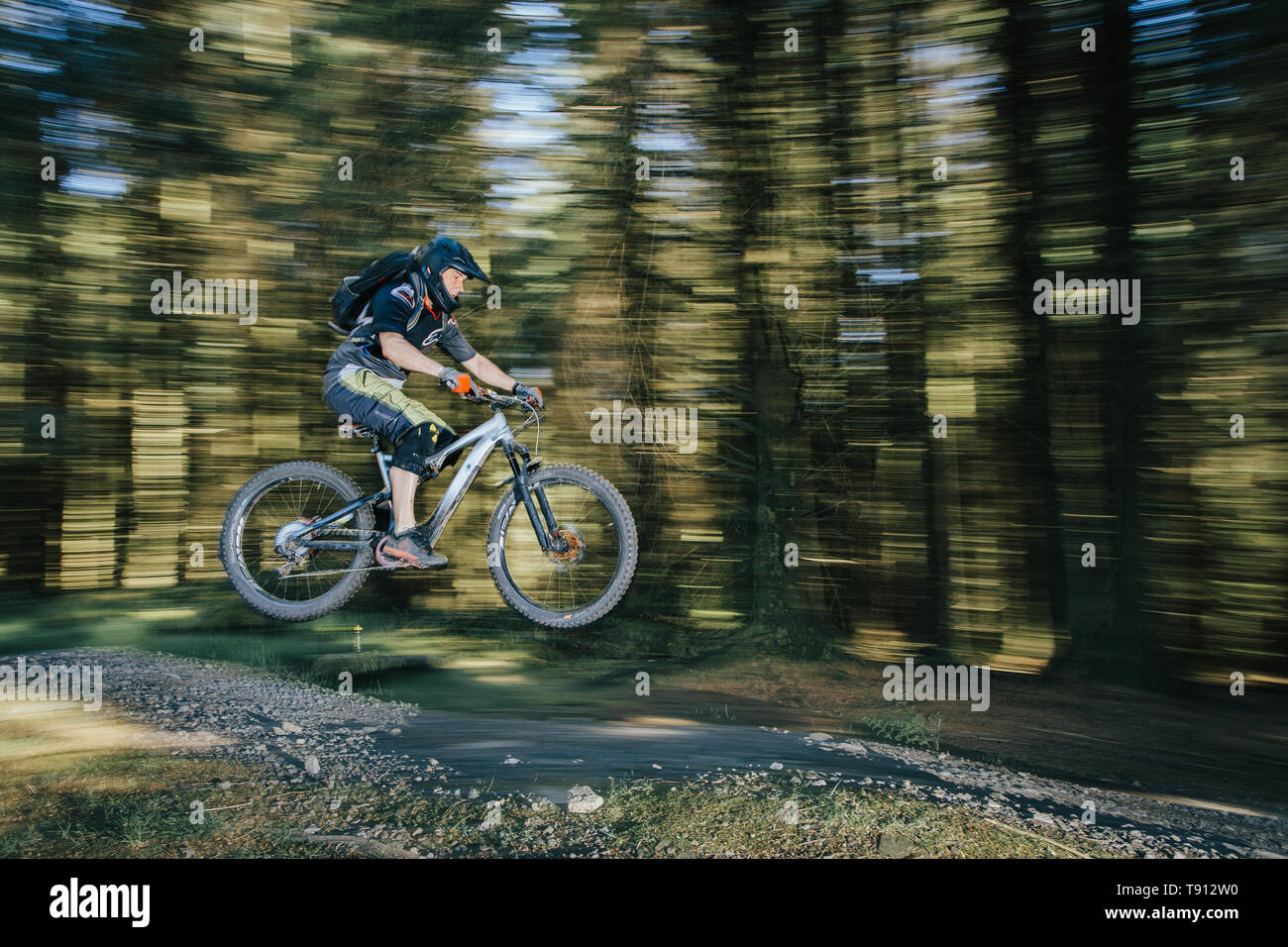 Electric Mountain bike or ebike being jumped at a Mountain Bike trail centre.  Shot at Bike Park Wales. Image taken to shows the speed of the riders. Stock Photo