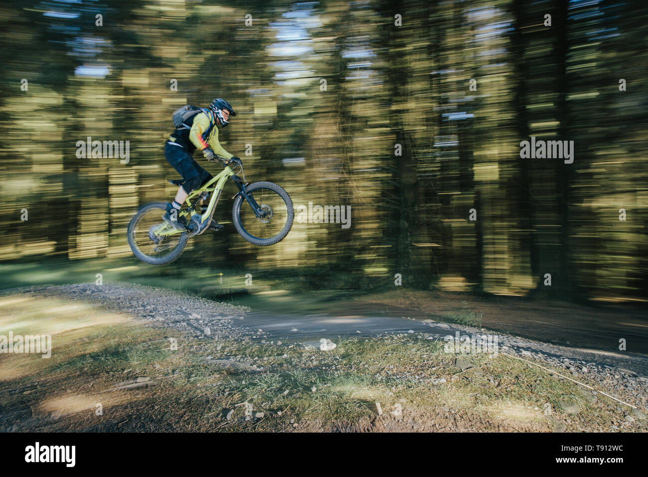 Electric Mountain bike or ebike being jumped at a Mountain Bike trail centre.  Shot at Bike Park Wales. Image taken to shows the speed of the riders. Stock Photo