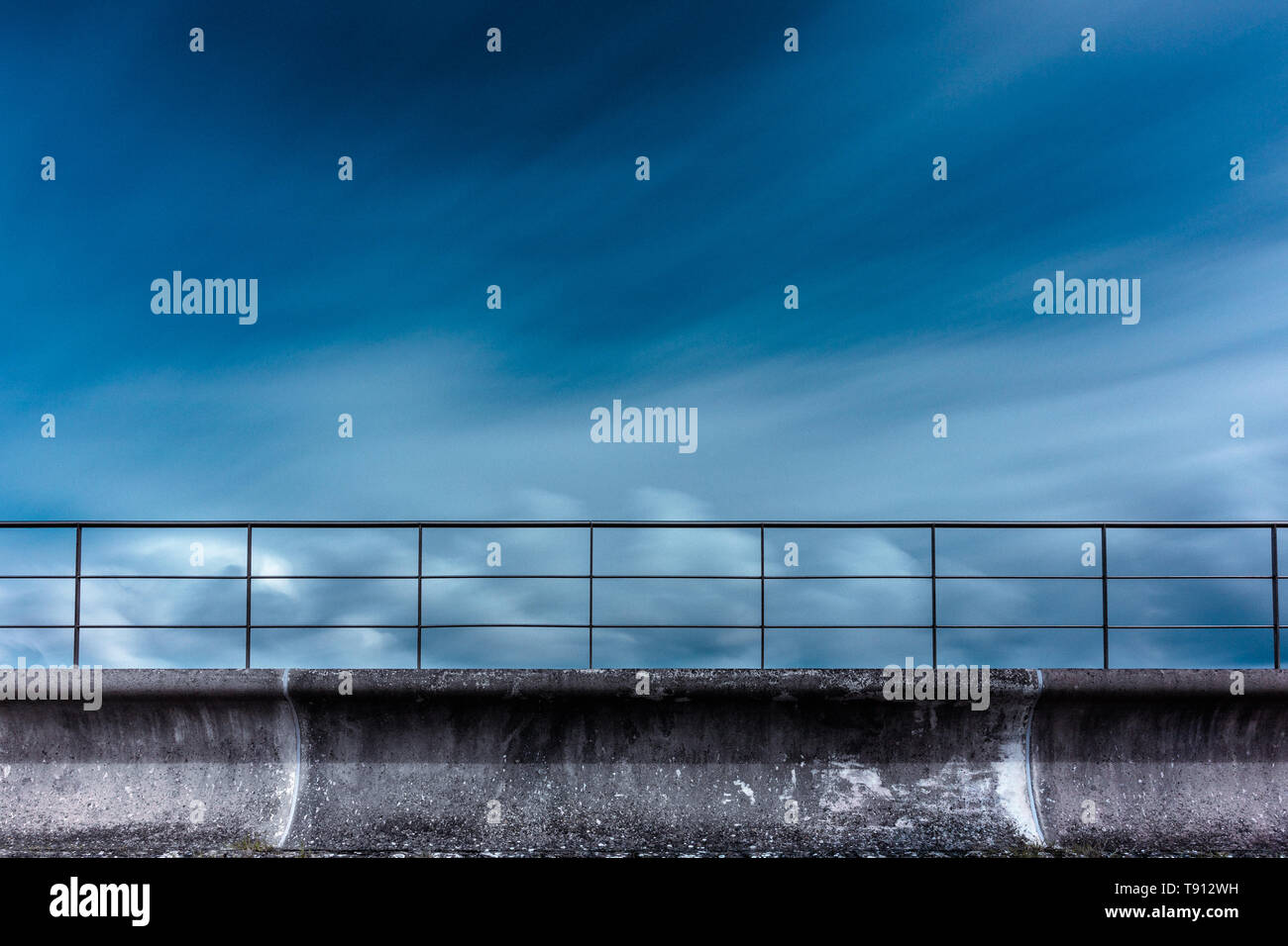 Sea wall at Severn River Crossing, highlighting the concrete against the clouds and sky using a long exposure to make the clouds soften and flow Stock Photo