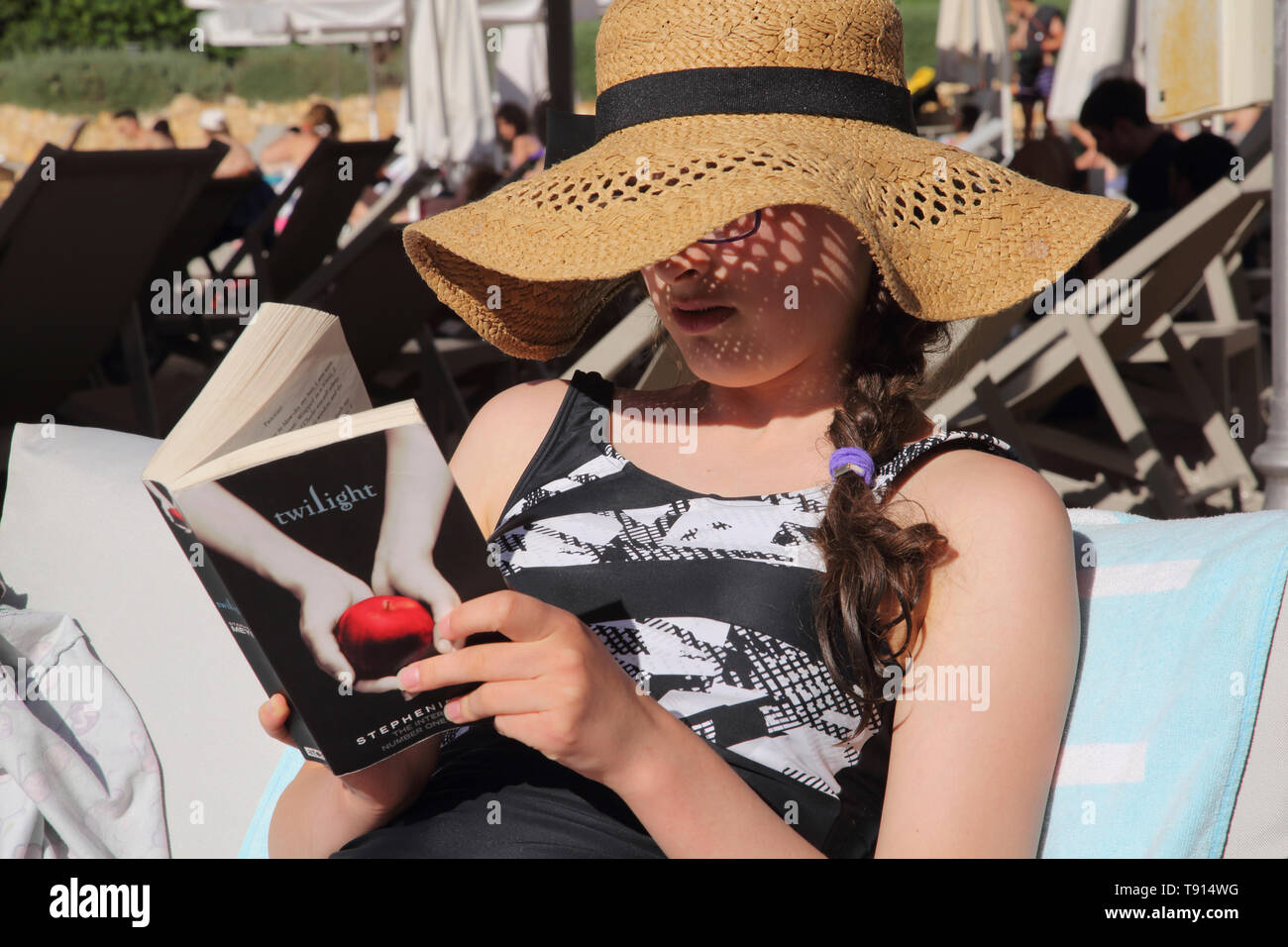 Vouliagmeni Attica Greece Lake Vouliagmeni Teenage Girl wearing Sun Hat and Reading Book Stock Photo