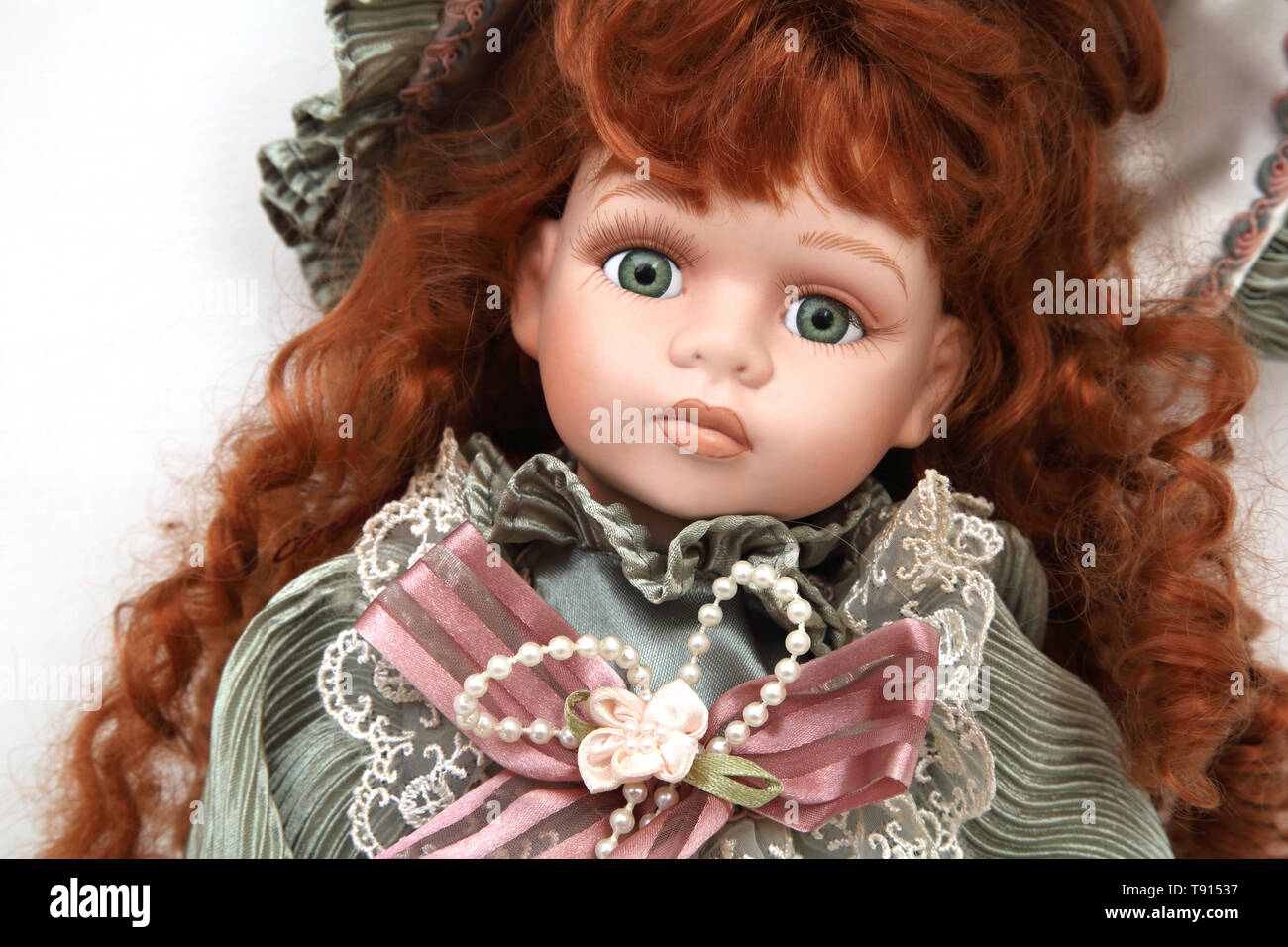 modern makeup doll face portrait toy red hair girl lying in green  background Stock Photo - Alamy