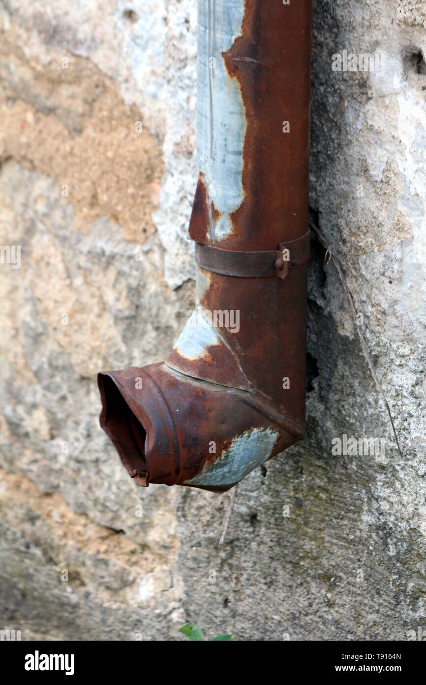 Almost completely rusted and beaten down gutter rainfall exit mounted