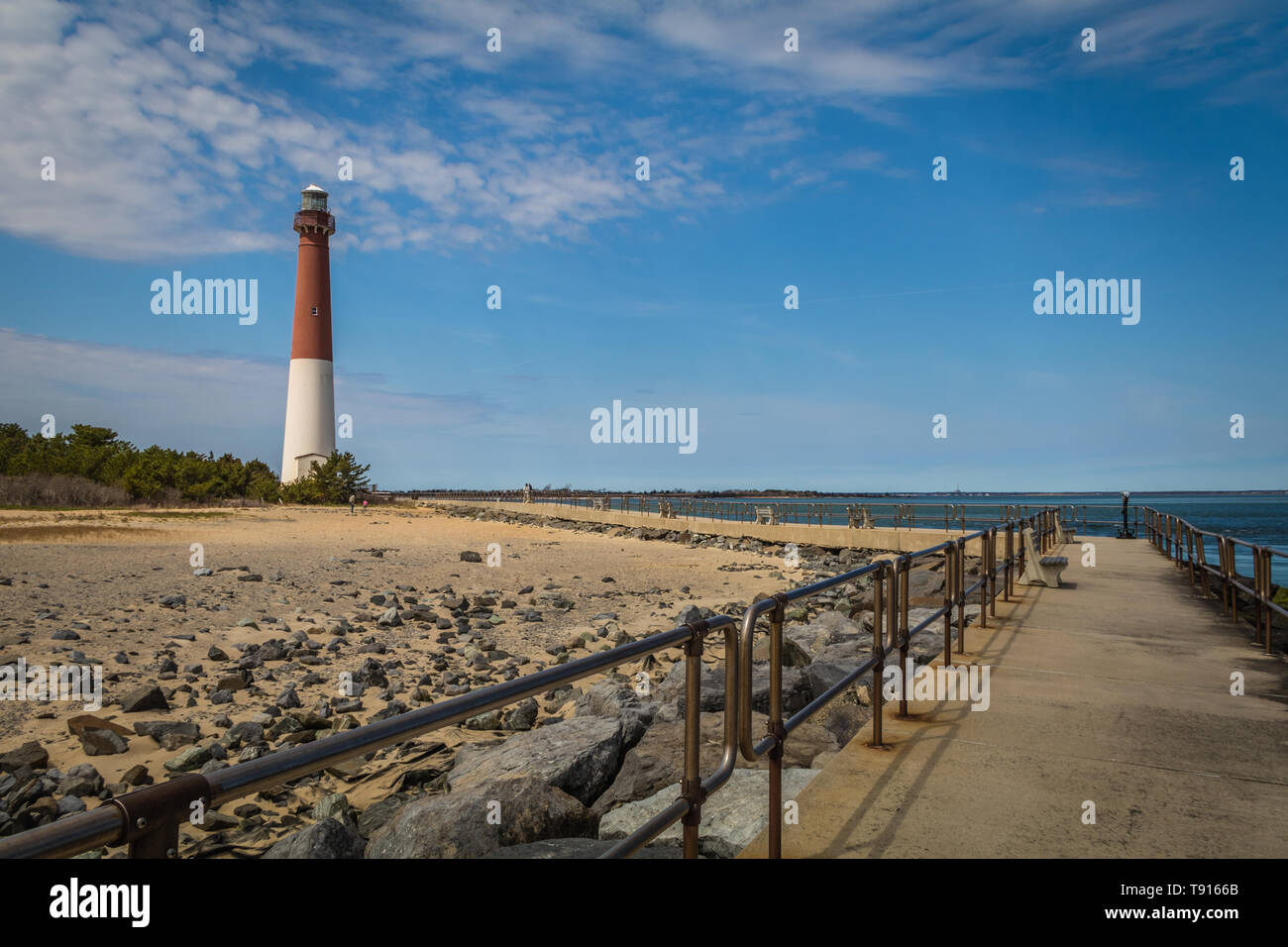 Barnegat Lighthouse on Long Beach Island, NJ, on a sunny spring day with blue sky dotted with