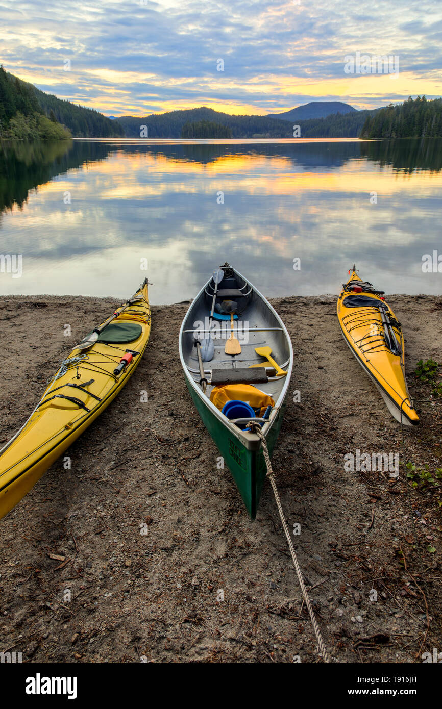 Kayaks and a canoe rest on the shore of Main Lake, in Main Lake Provincial Park on Quadra Island, British Columbia, Canada Stock Photo
