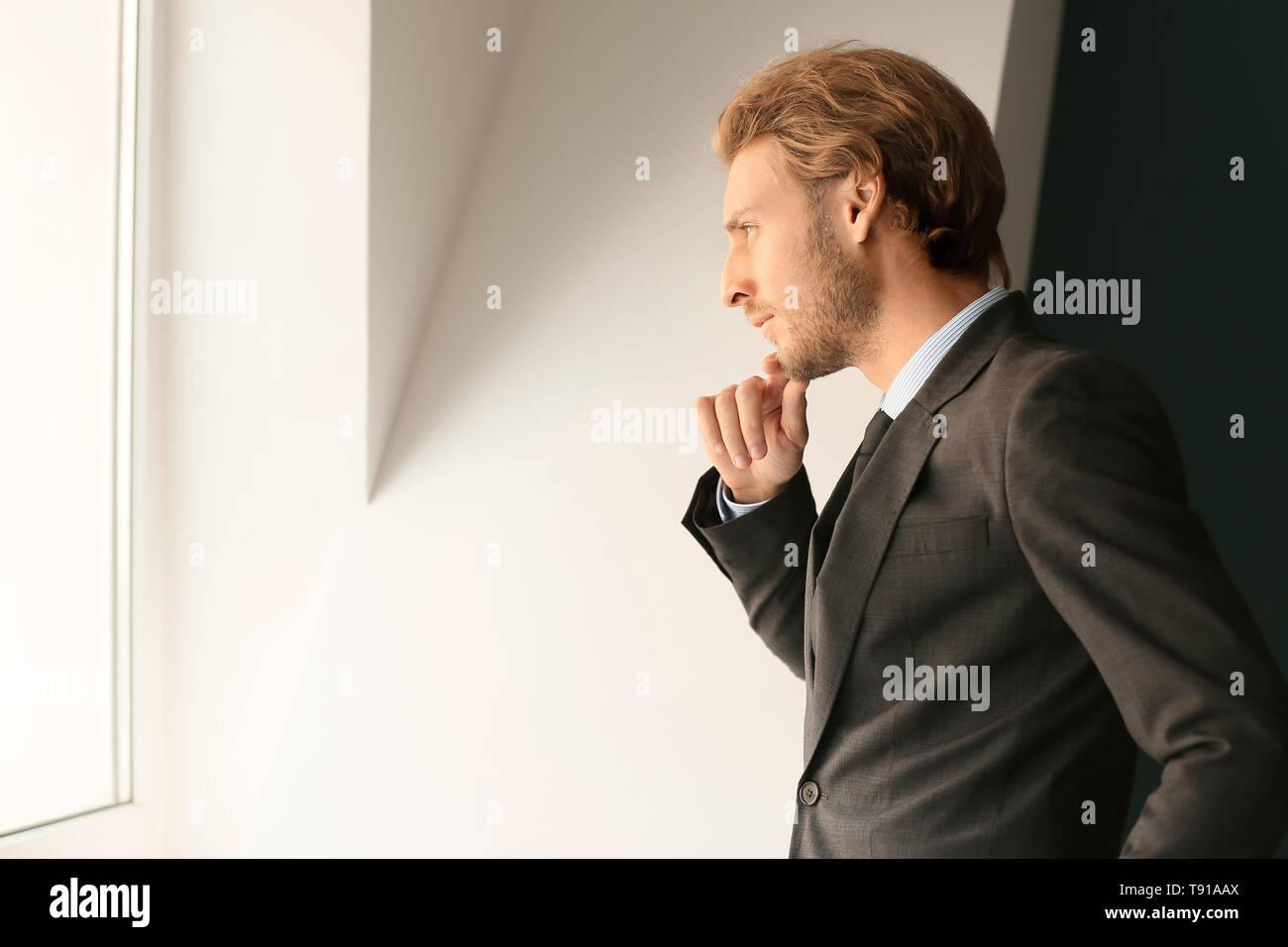 Thoughtful young businessman looking through window Stock Photo