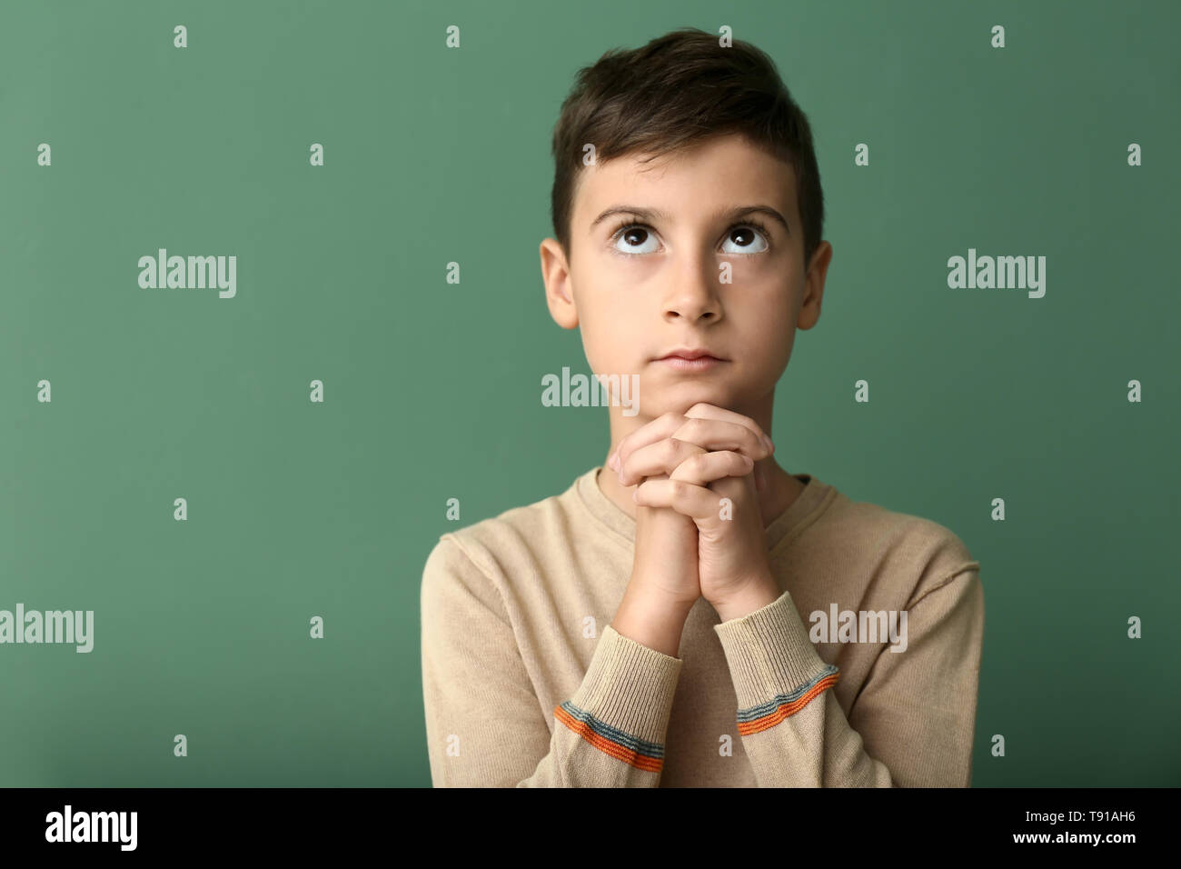Little boy praying on color background Stock Photo - Alamy
