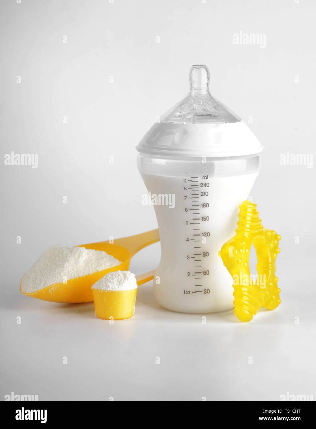 Bottle of milk for baby and measuring scoops with powder on light