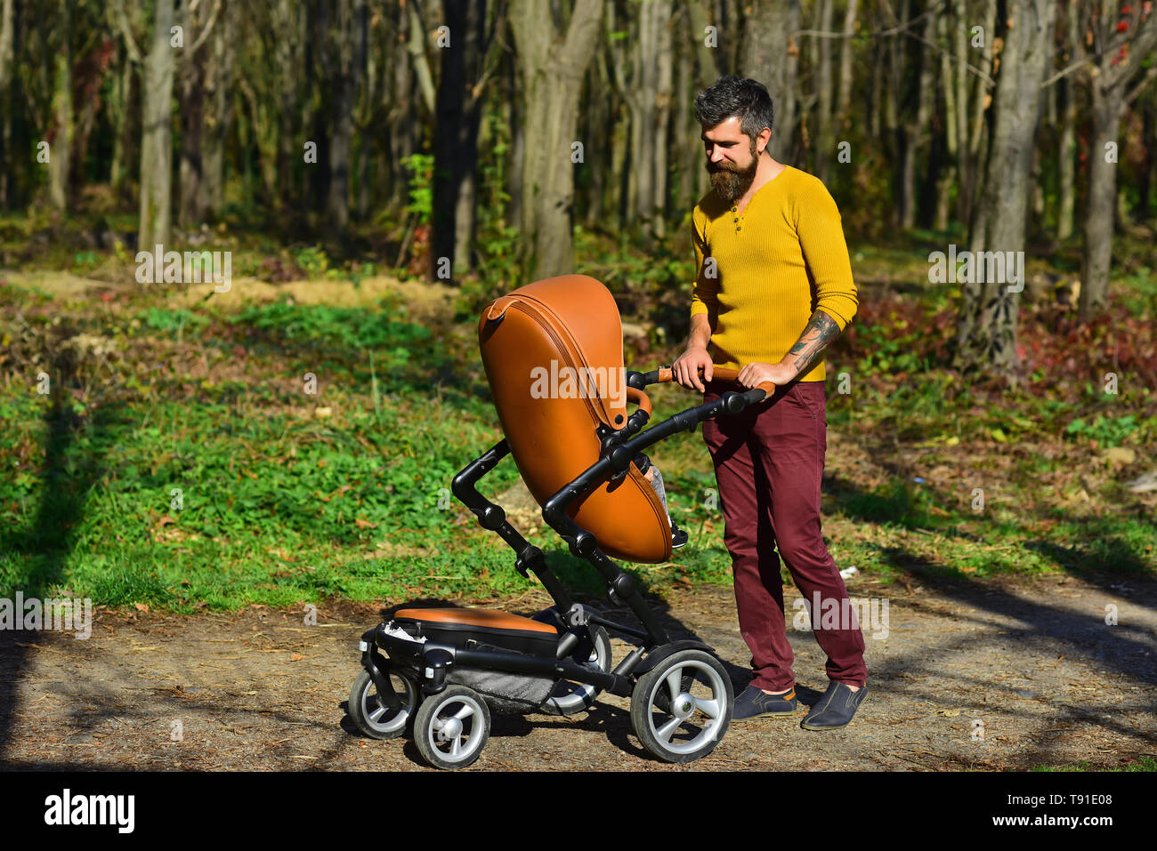 Father with pram on walk. Father push baby stroller in autumn park. This is what an awesome dad looks like Stock Photo