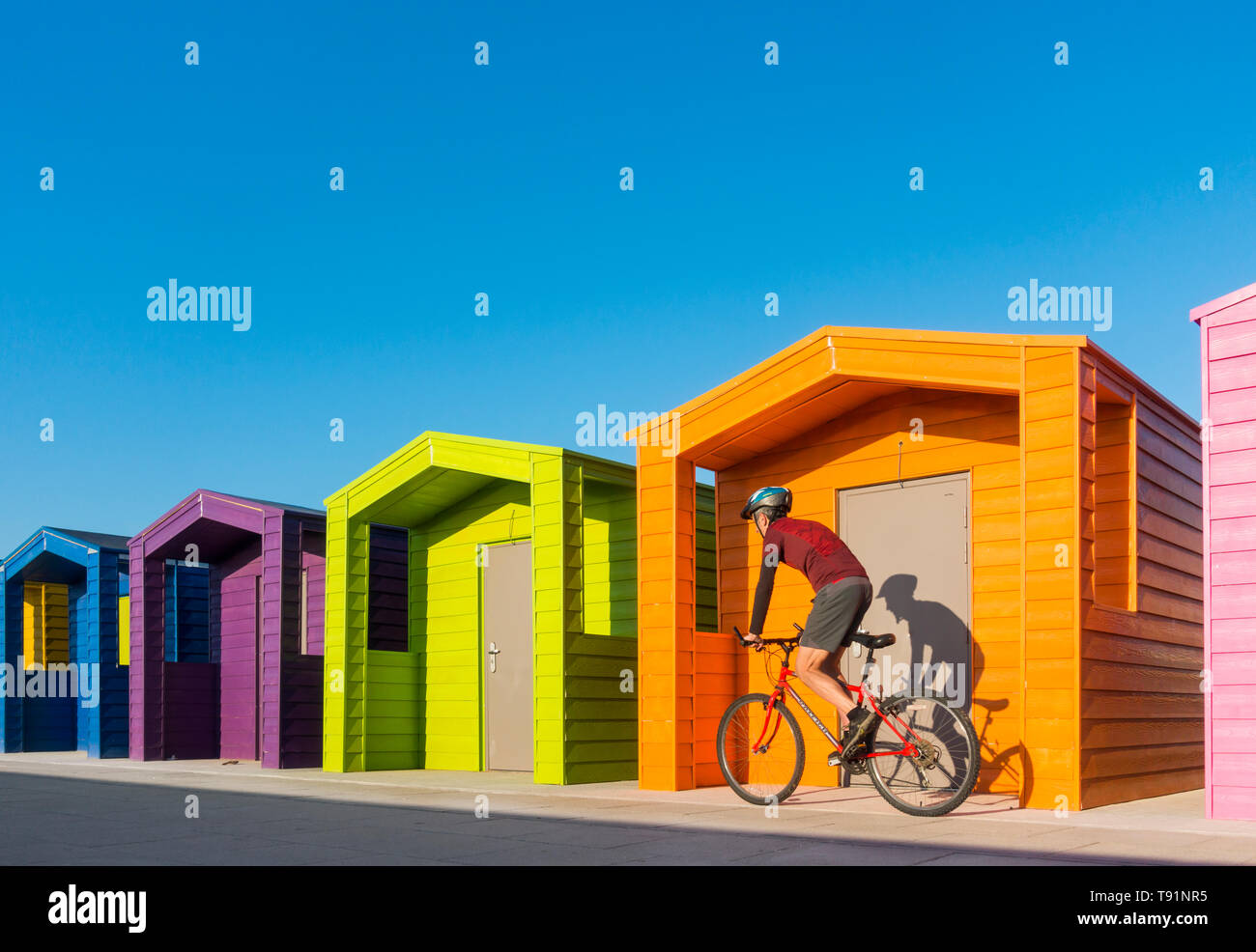 Mountain biker, cyclist riding past colourful beach huts at Seaton Carew. UK Stock Photo
