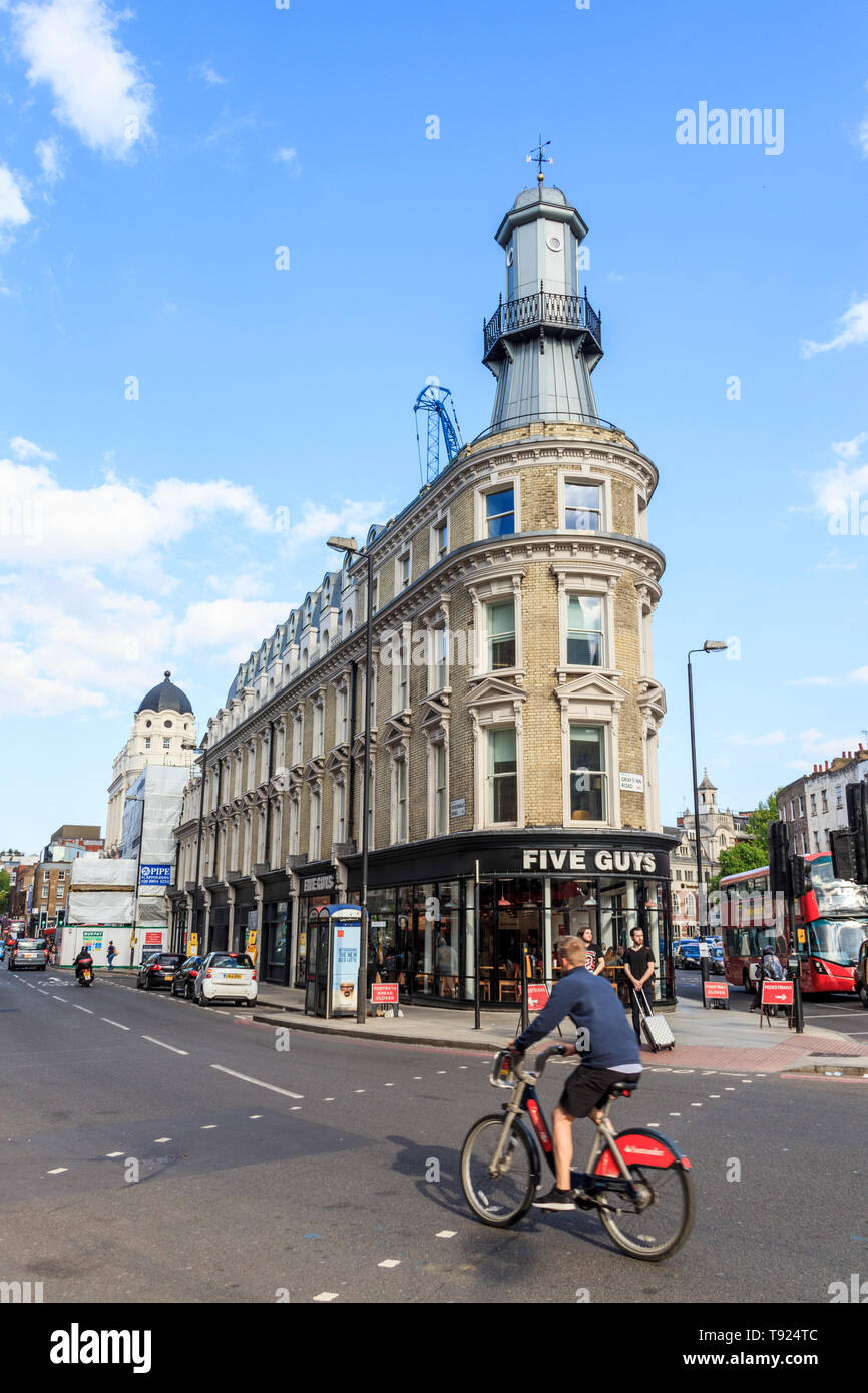 A cyclist on a Santander bike passes The Lighthouse, originally an oyster bar, now a Five Guys burger restaurant, King's Cross, London, UK, 2019 Stock Photo