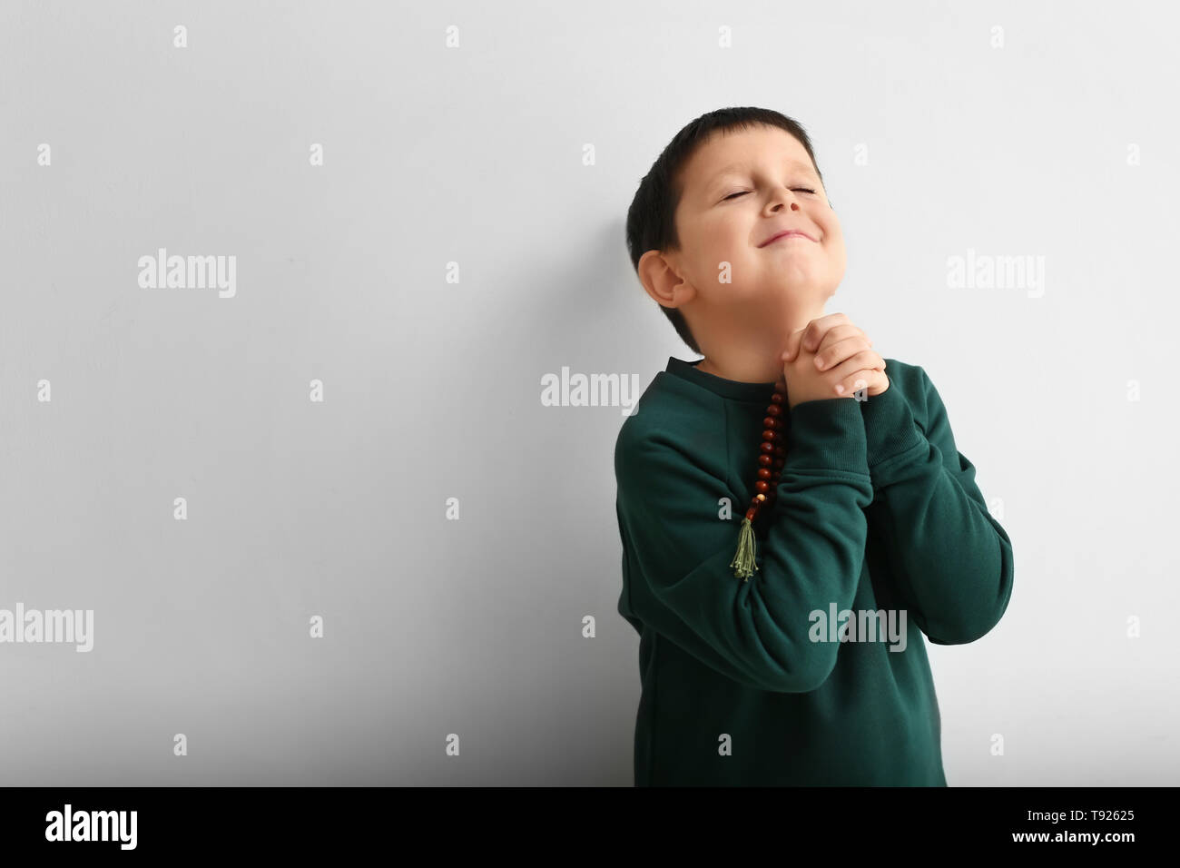 Little boy praying on light background Stock Photo - Alamy