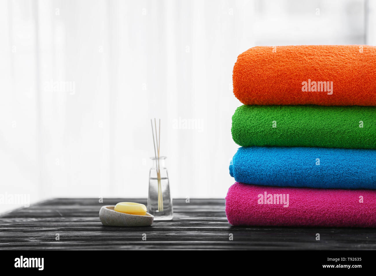 Folded bright terry towels and soap on wooden table Stock Photo