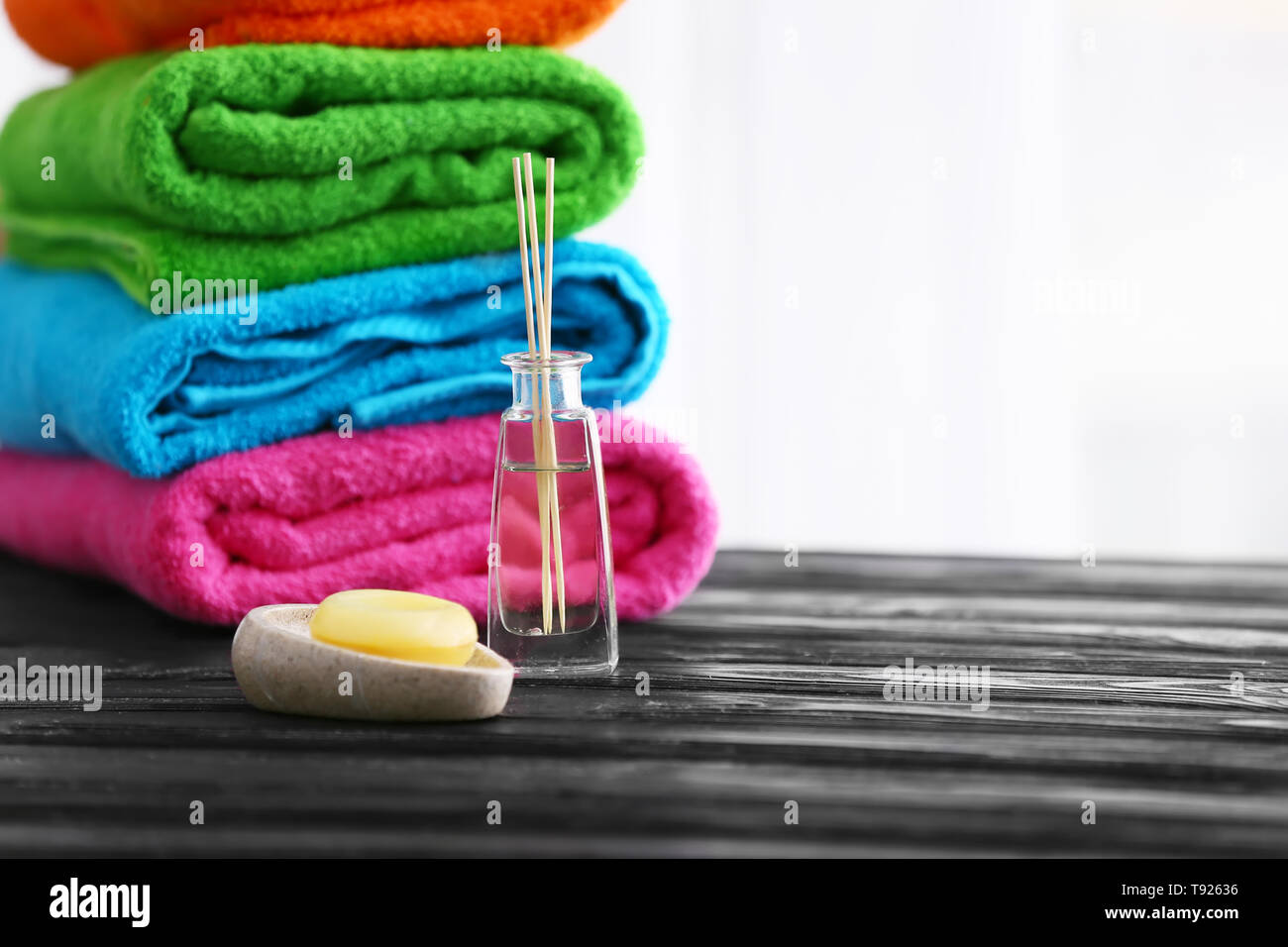 Soap and folded bright terry towels on wooden table Stock Photo