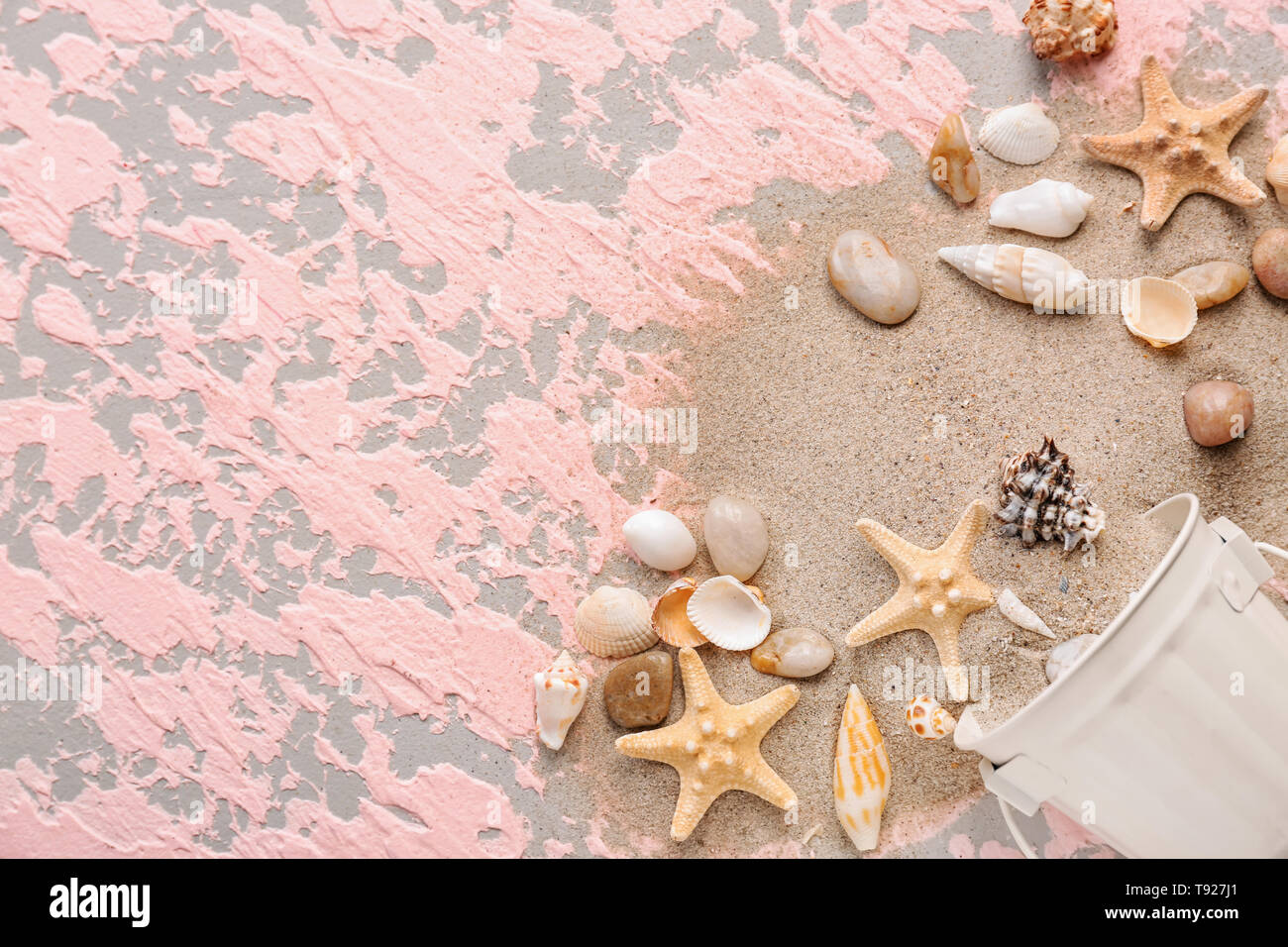 Overturned bucket with with different sea shells and sand on color ...