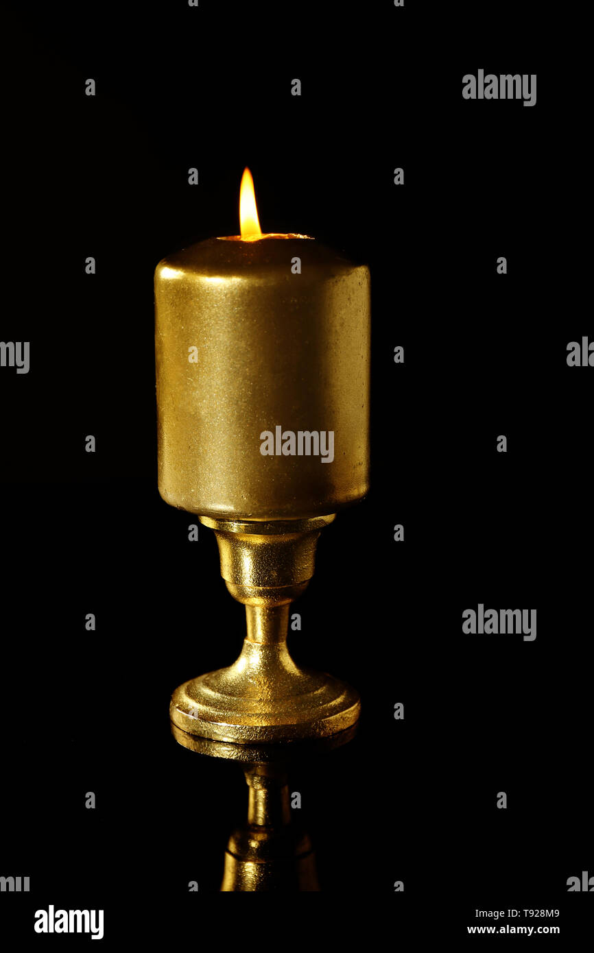 Golden candle on black background Stock Photo
