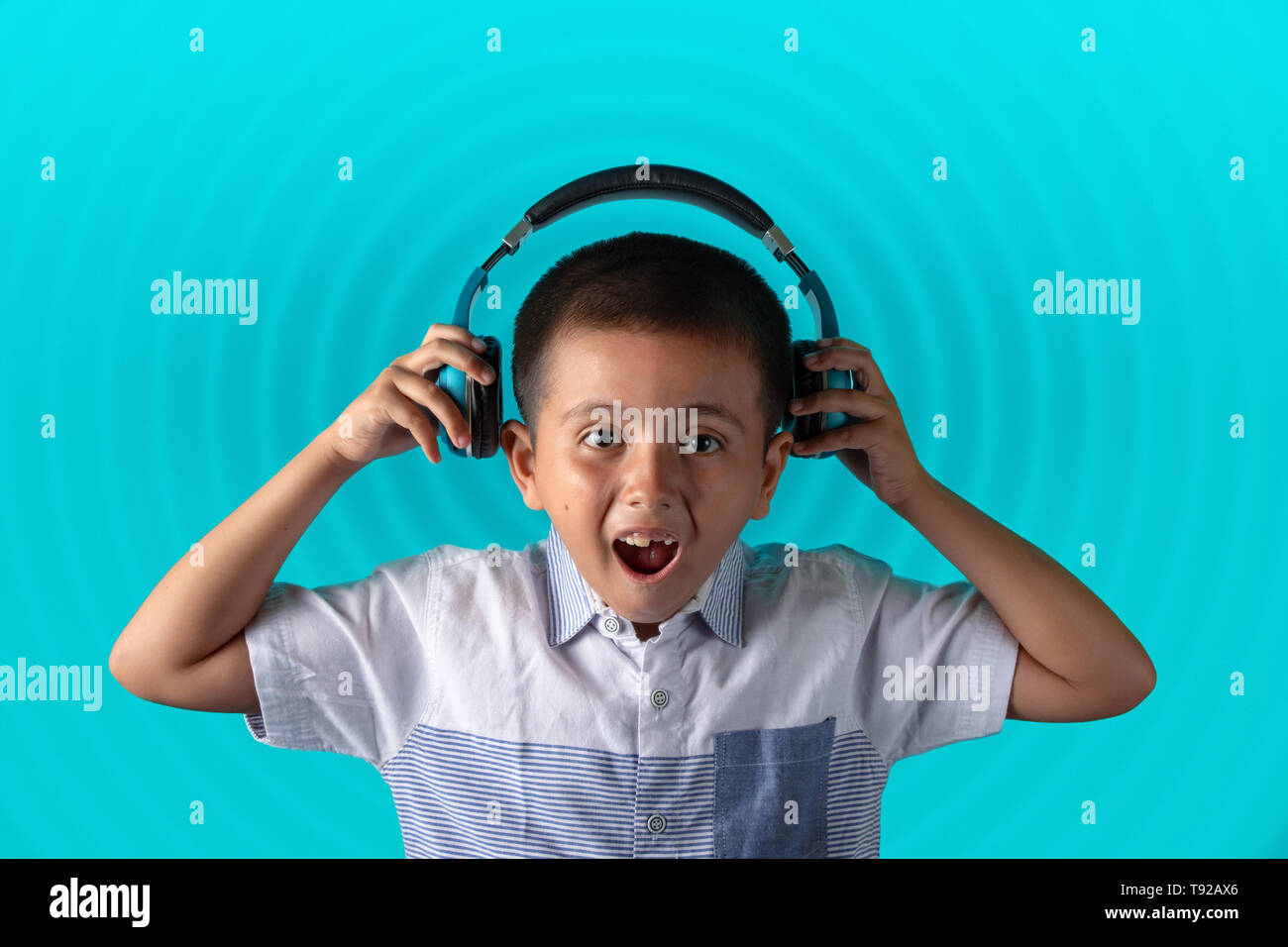 Young boy holding and looking at aux cable while wearing headphones.  Music concept image with copy space for text. Stock Photo