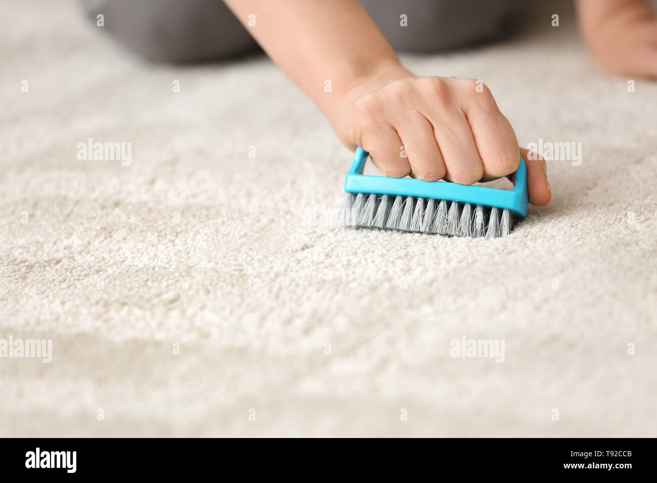 Woman cleaning carpet with brush at home Stock Photo - Alamy